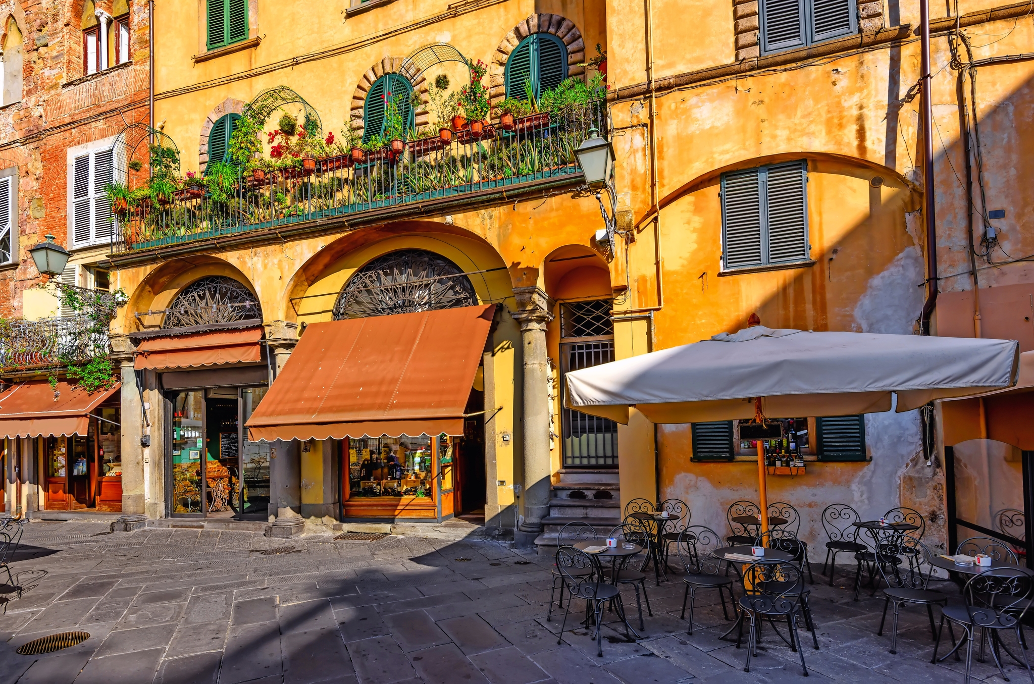 Lucca in der Toskana, Italien Bunte Fassade eines Restaurants mit Außensitzbereich auf einem sonnigen Platz.