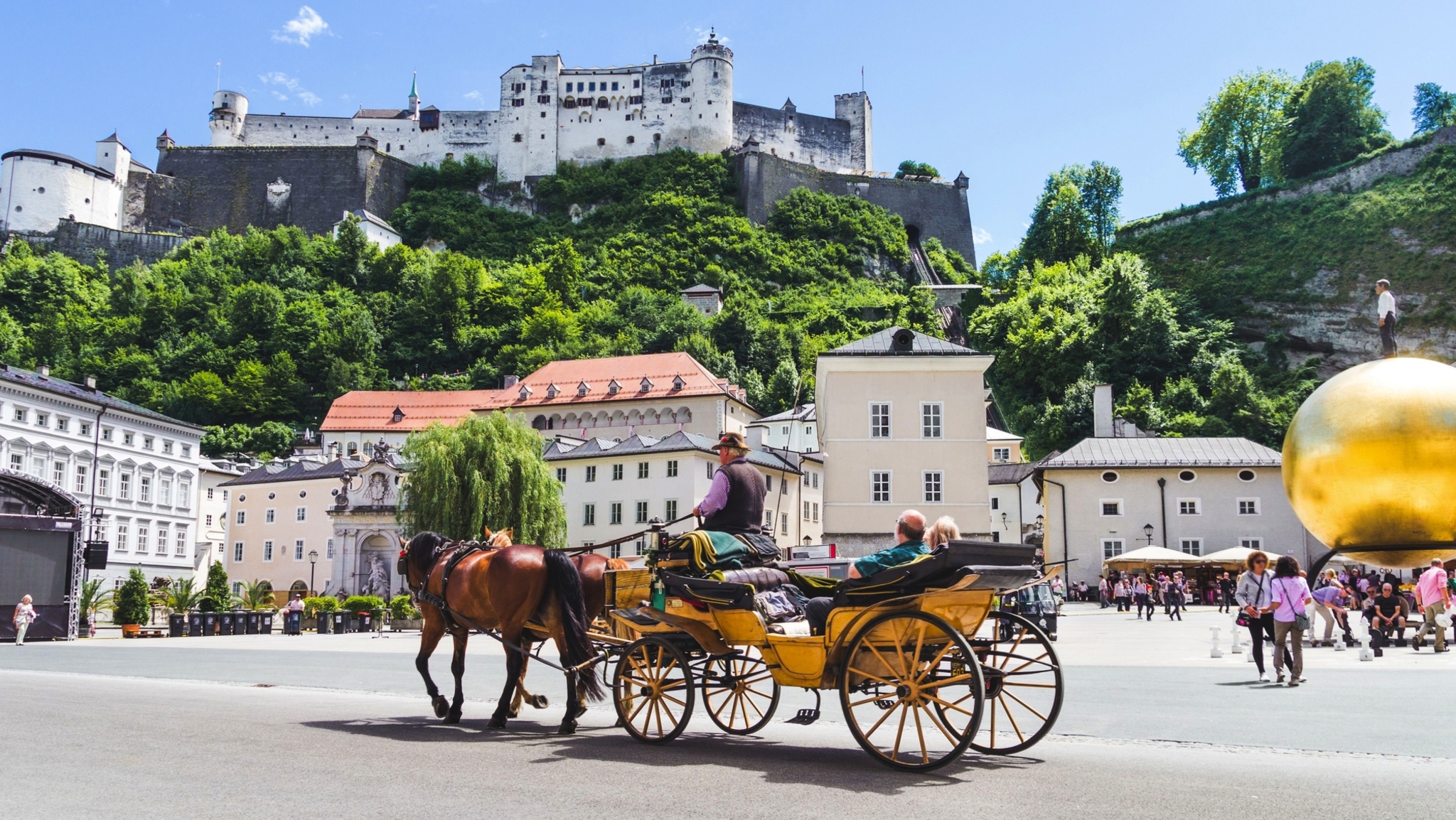 Pferdekutsche auf Stadtplatz mit Festung im Hintergrund.