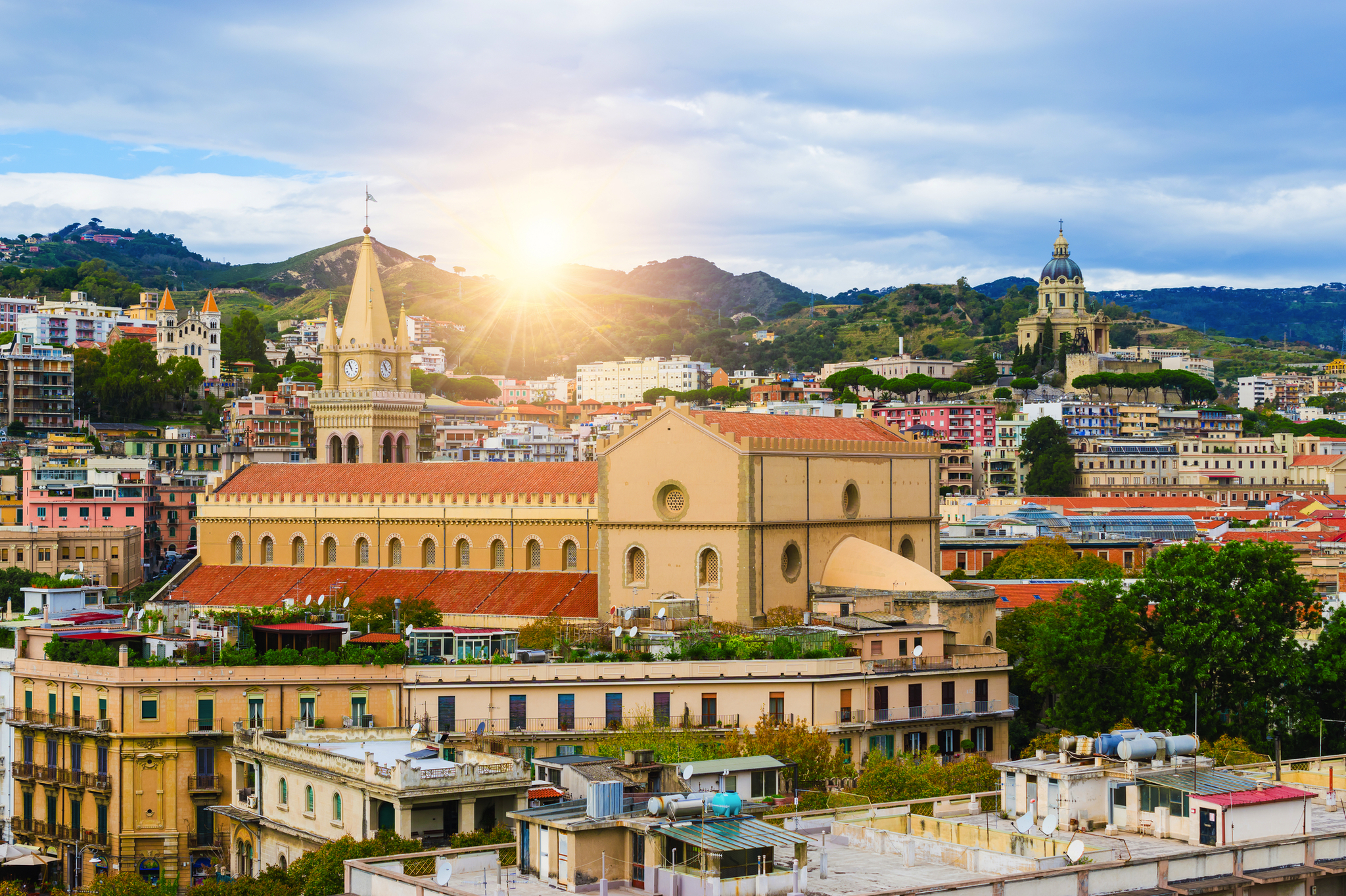 Kirche in italienischer Stadtlandschaft bei Sonnenuntergang, umgeben von Hügeln und Gebäuden.