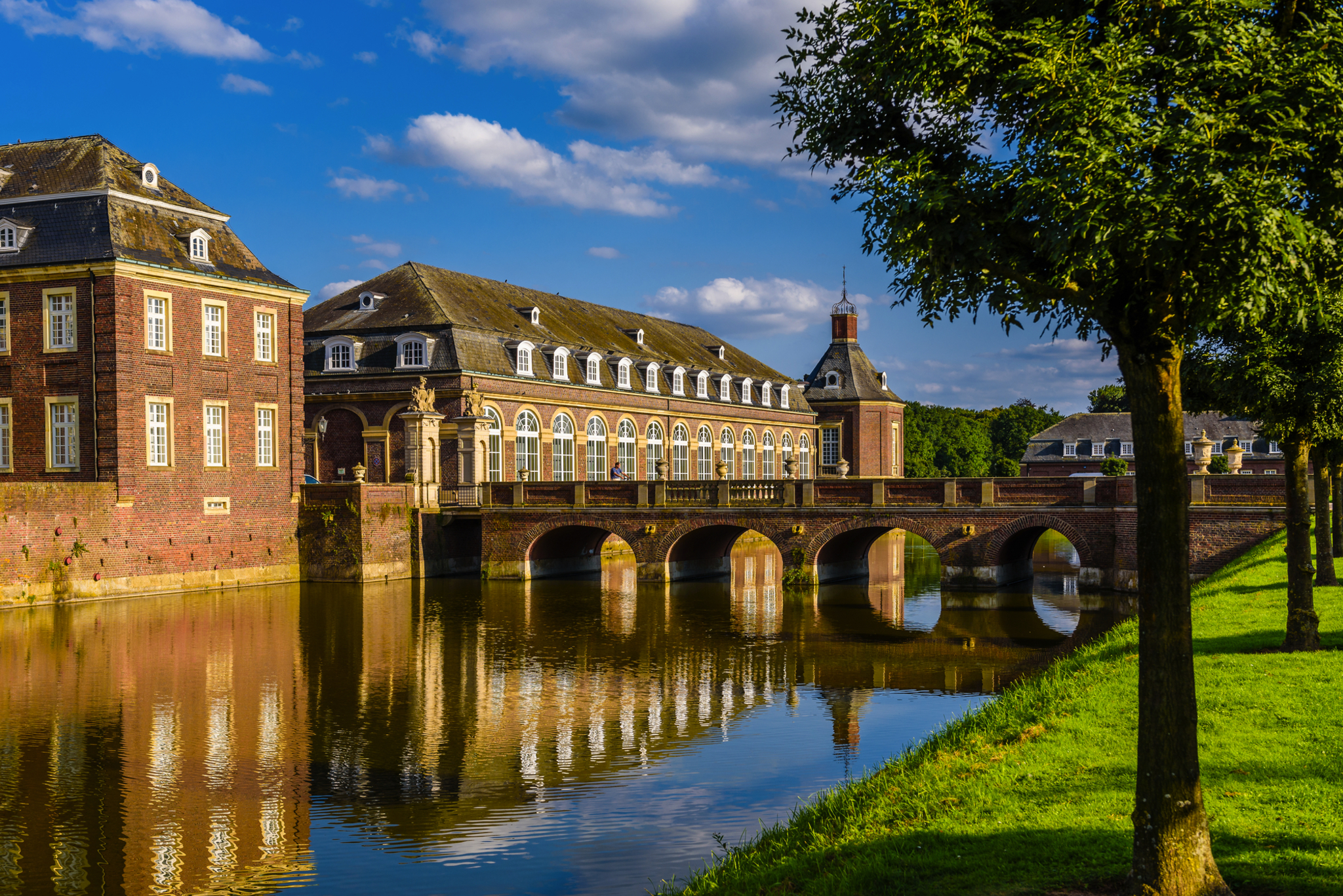 Historisches Schloss mit Wassergraben bei blauem Himmel.