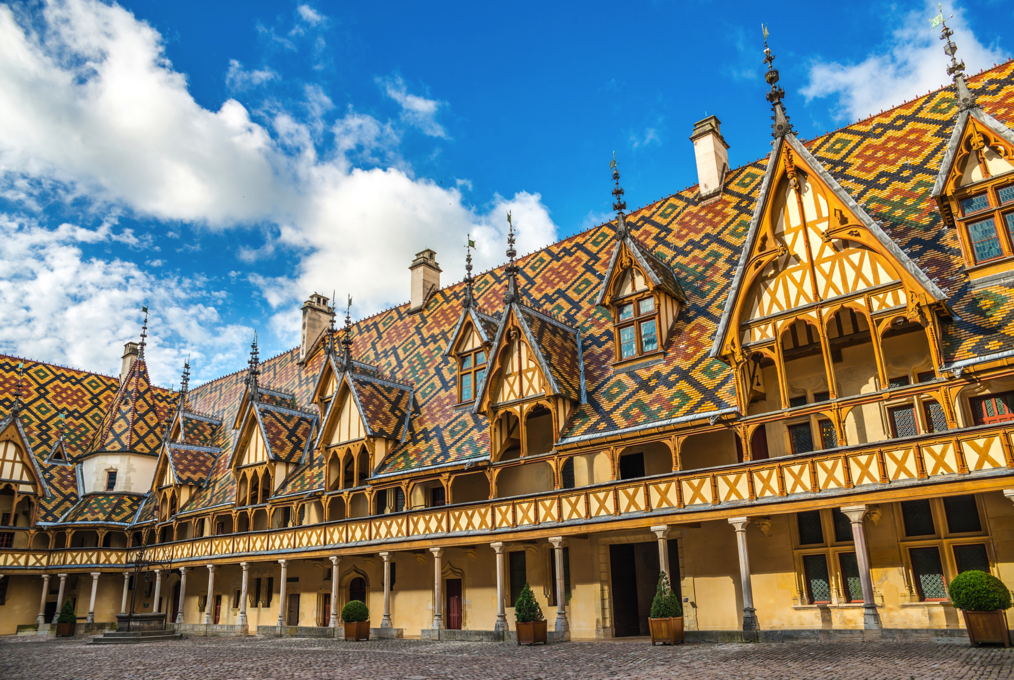 Hôtel-Dieu in Beaune mit buntem, geometrischem Dach und Innenhofansicht.