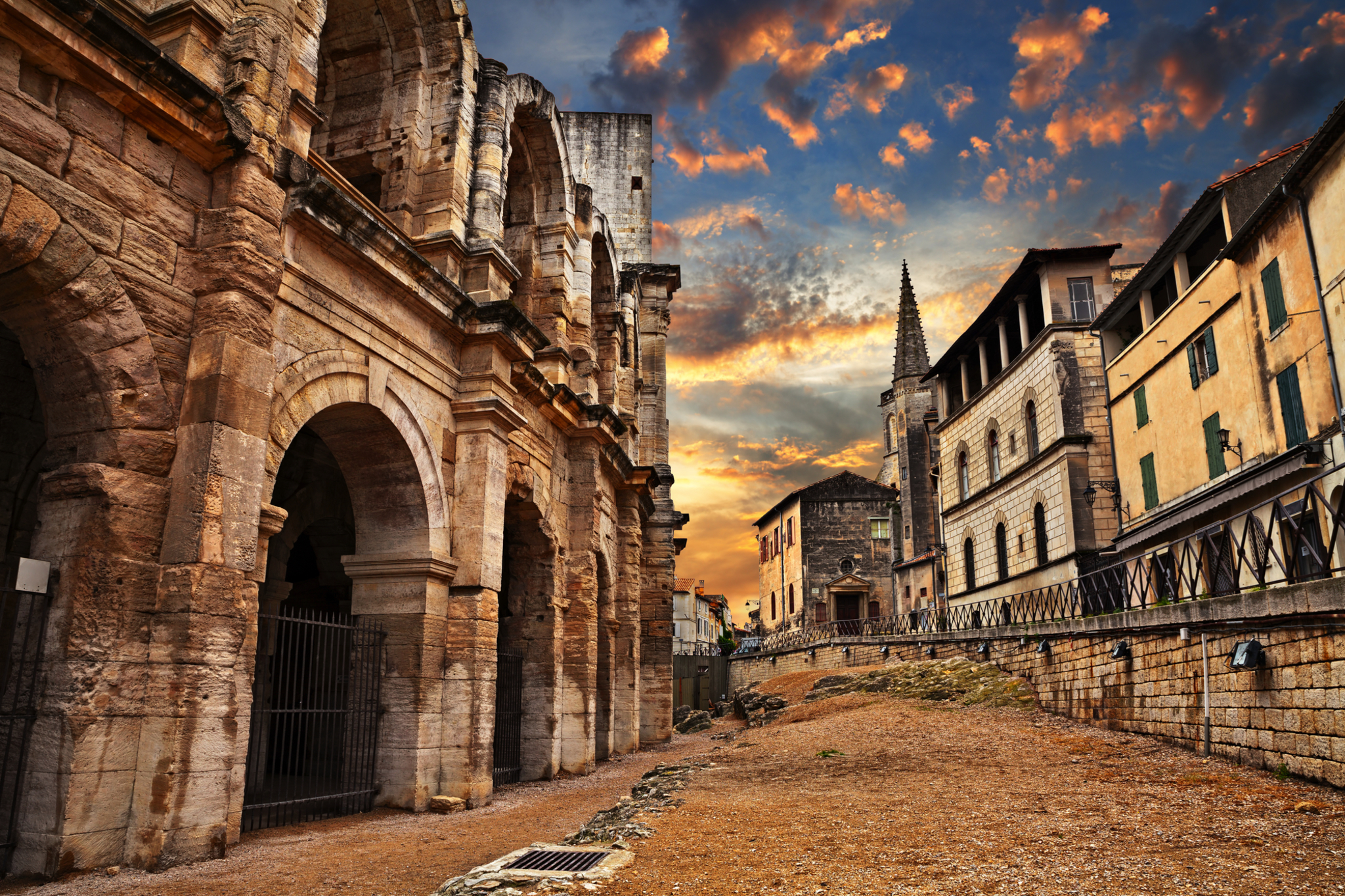 Römisches Amphitheater bei Sonnenuntergang mit historischen Gebäuden.
