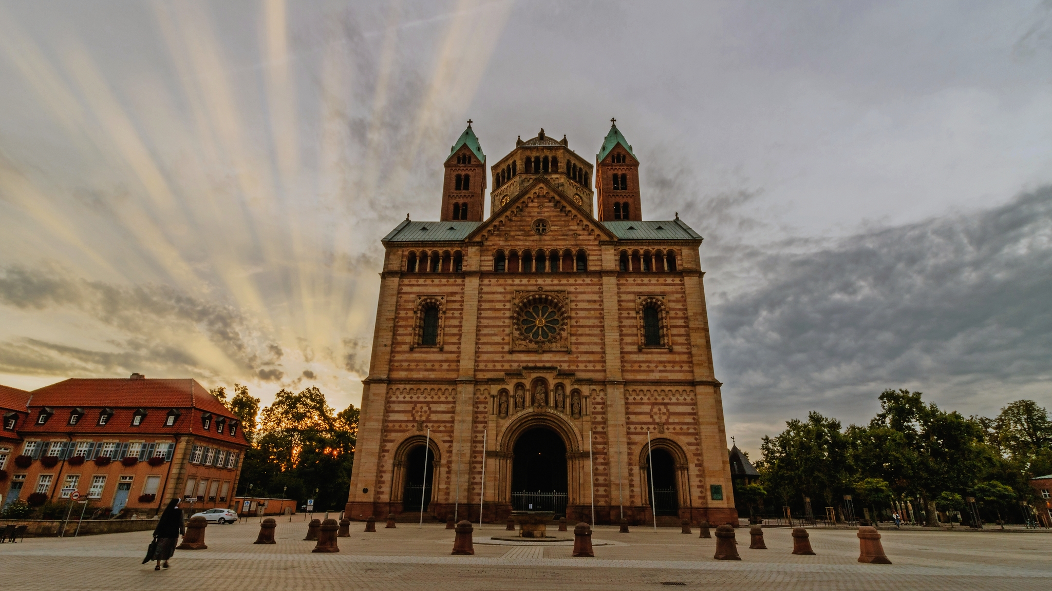 Westfassade eines Doms bei Sonnenaufgang, Himmel mit Strahlen.