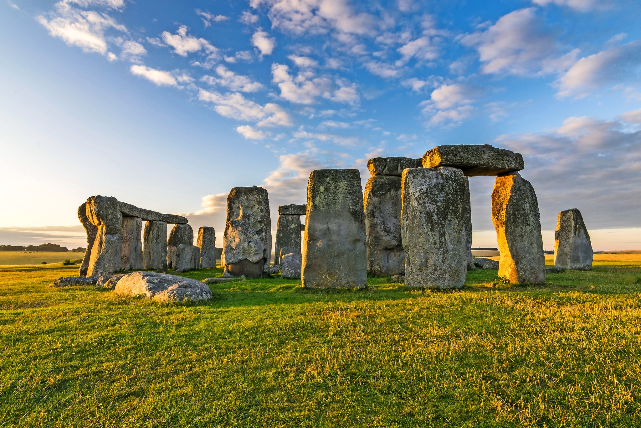 Steinkreis von Stonehenge bei Sonnenuntergang, mit blauem Himmel und Wolken.