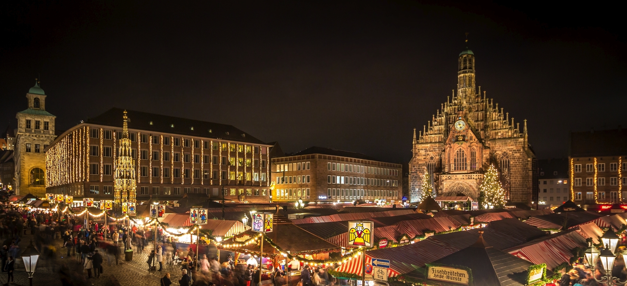 Historischer Weihnachtsmarkt bei Nacht mit beleuchteten Ständen und Kirche im Hintergrund.
