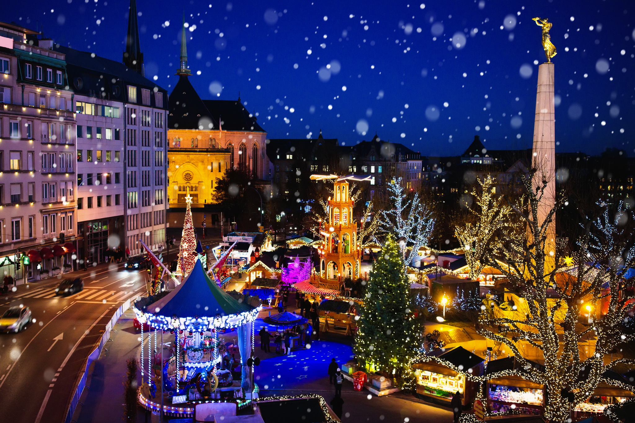 Weihnachtsmarkt bei Nacht mit Lichtern und Schnee in einer Stadt.