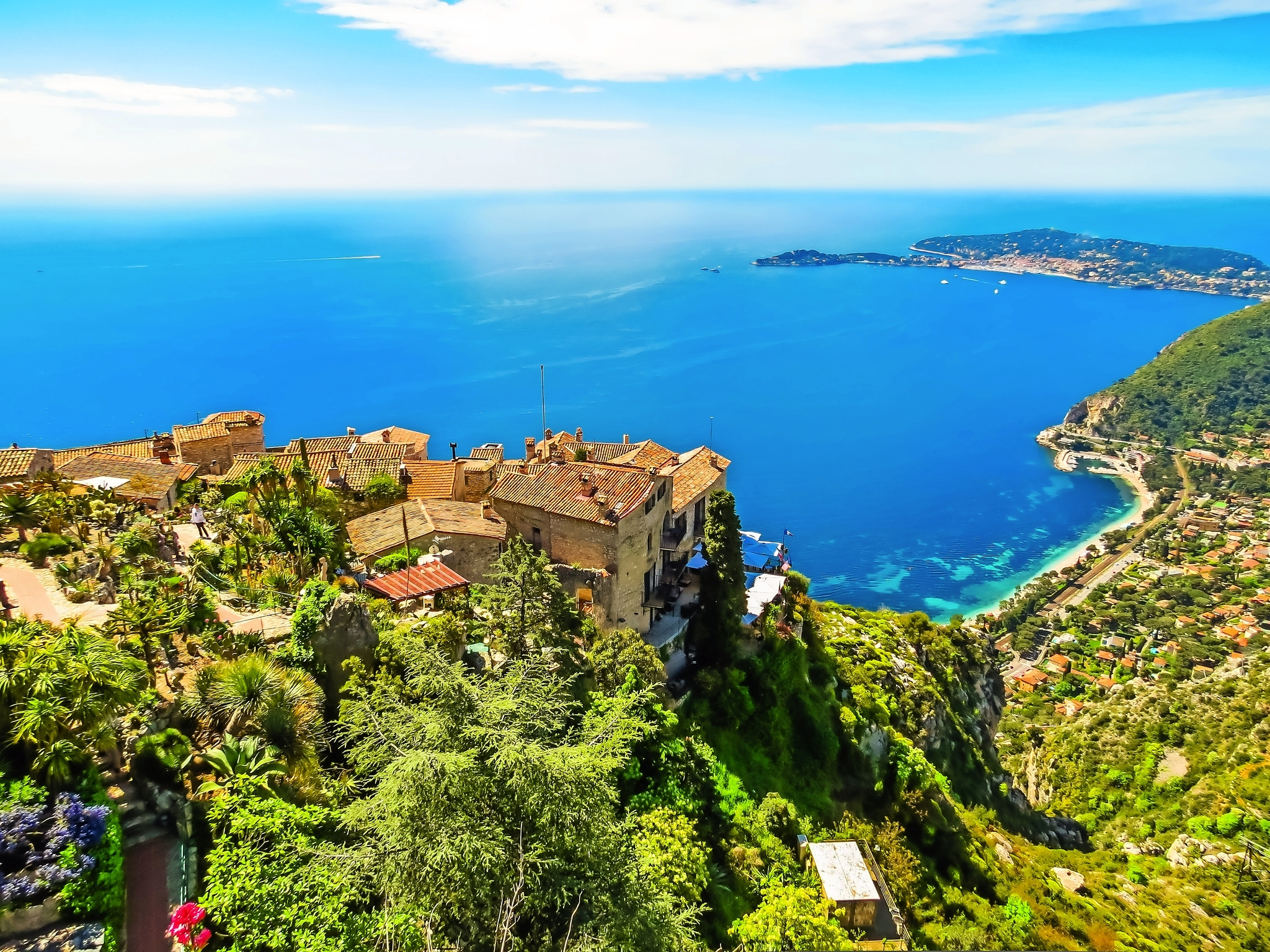 Mittelmeer-Küstenlandschaft mit Dorf auf Hügel und weitem Meerblick.
