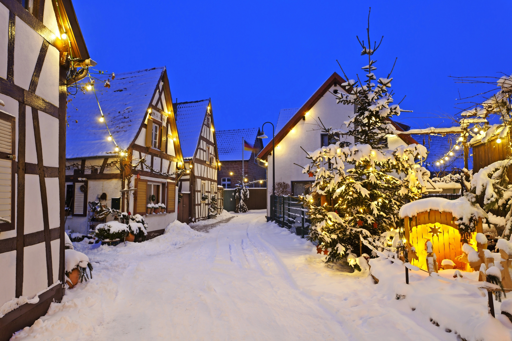 Verschneite Dorfstraße mit Fachwerkhäusern und weihnachtlicher Beleuchtung