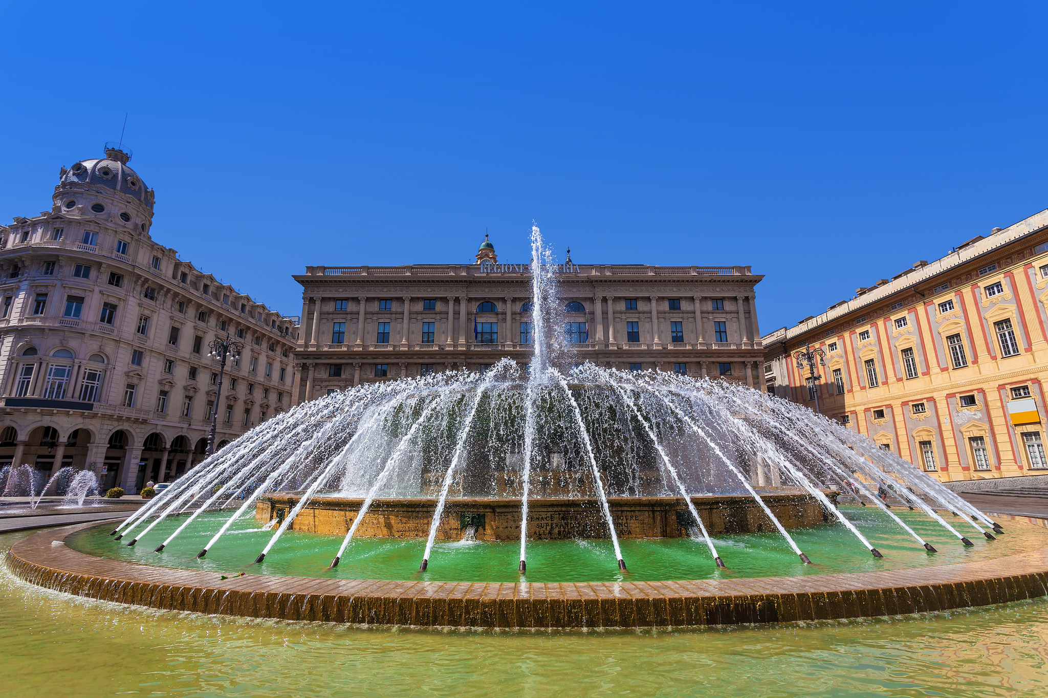 Großer Springbrunnen auf einem Platz vor historischen Gebäuden.