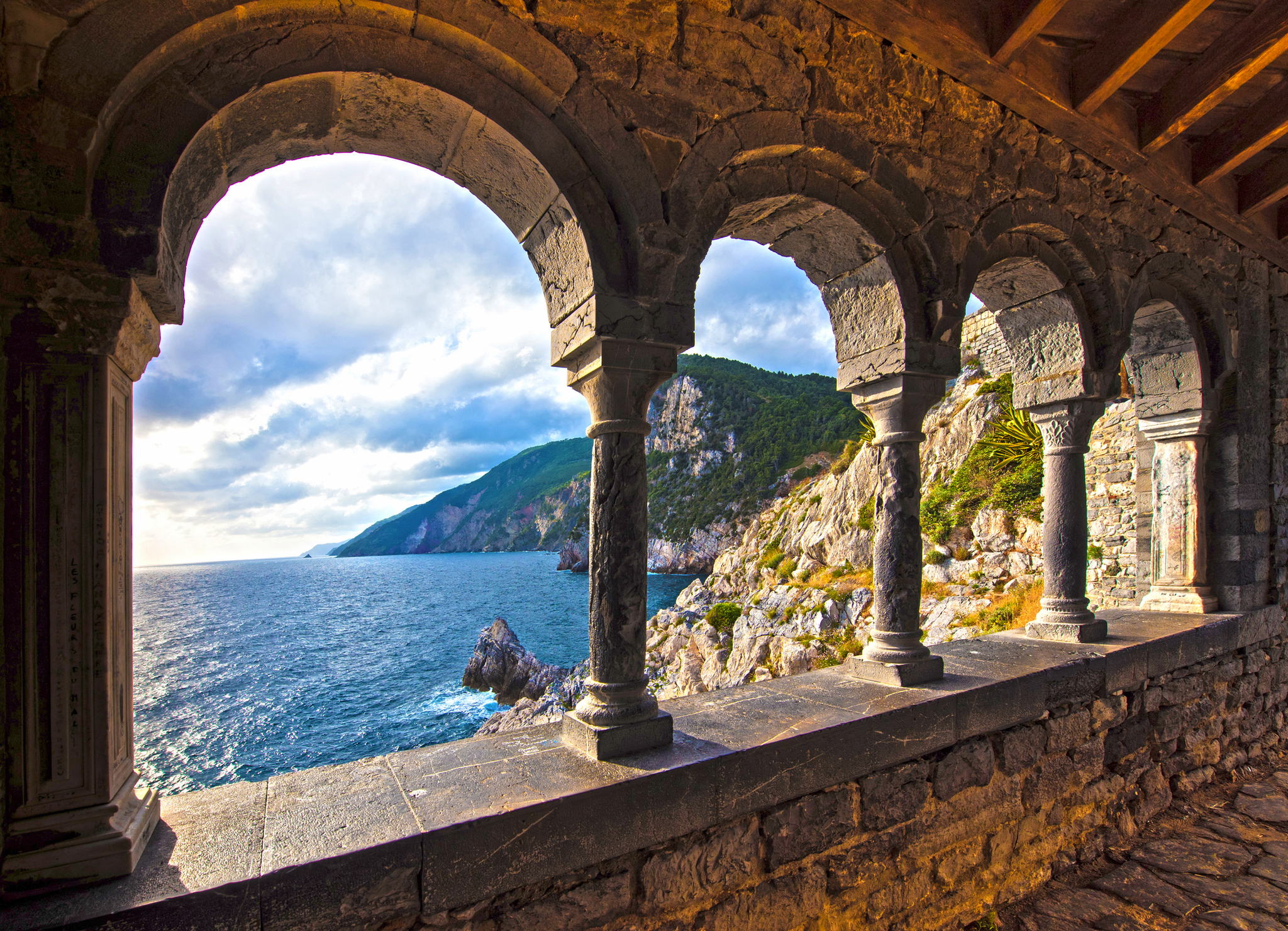 Blick auf das Meer durch die Burg und die gotische Kirche St. Peter Bögen in Porto Venere Felsbögen mit Blick auf das Meer und felsige Küste bei Sonnenuntergang.
