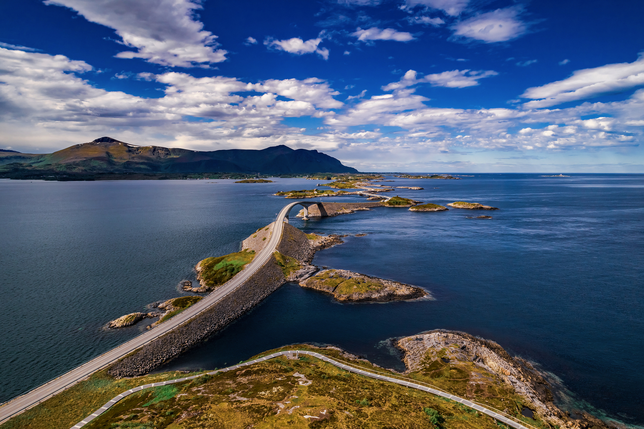 Brücke über das Meer mit Bergen und blauem Himmel im Hintergrund