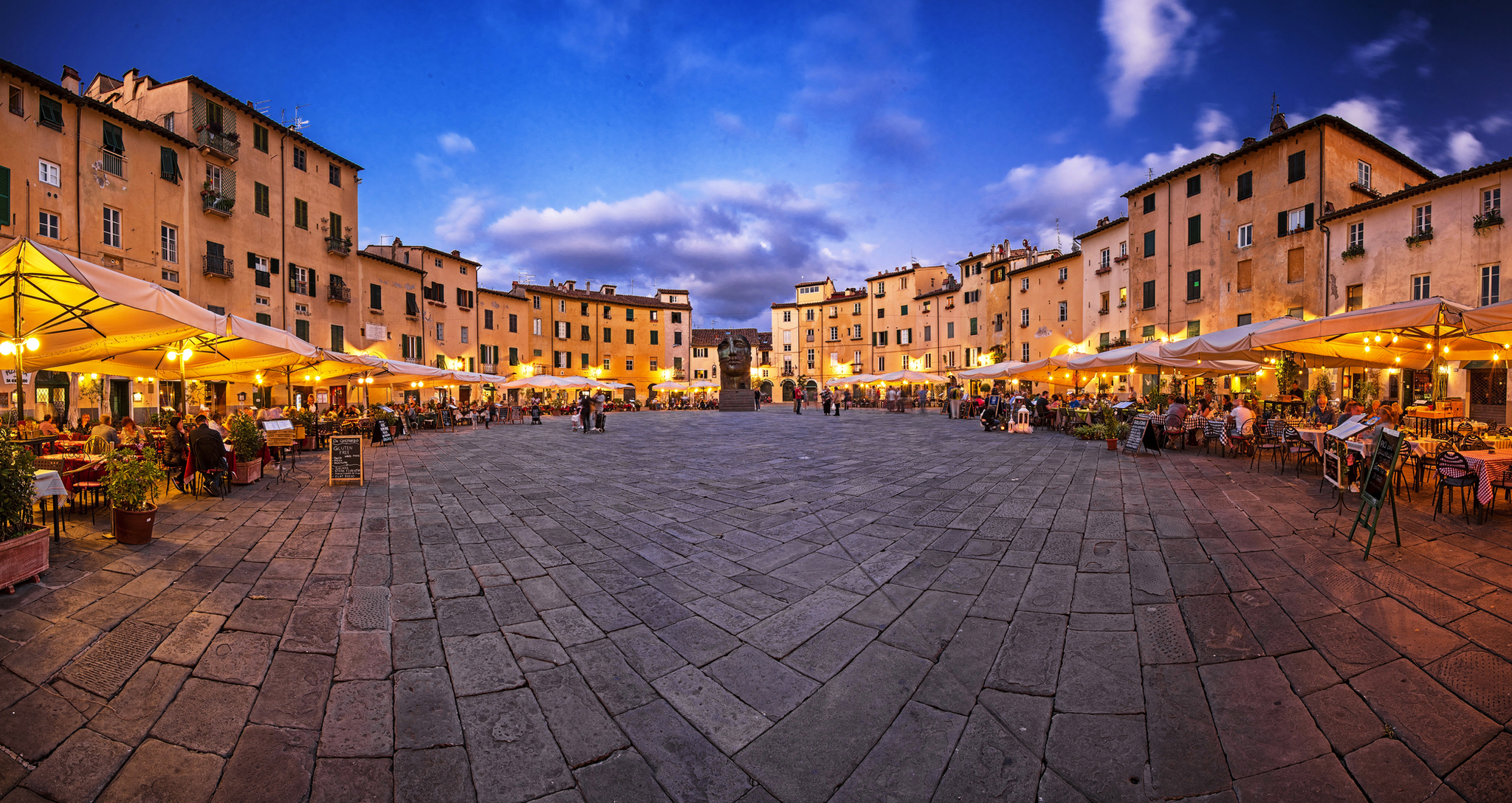 Piazza dell' Anfiteatro in Lucca, Italien Abendlicher Platz mit Restaurants und beleuchteten Sonnenschirmen.