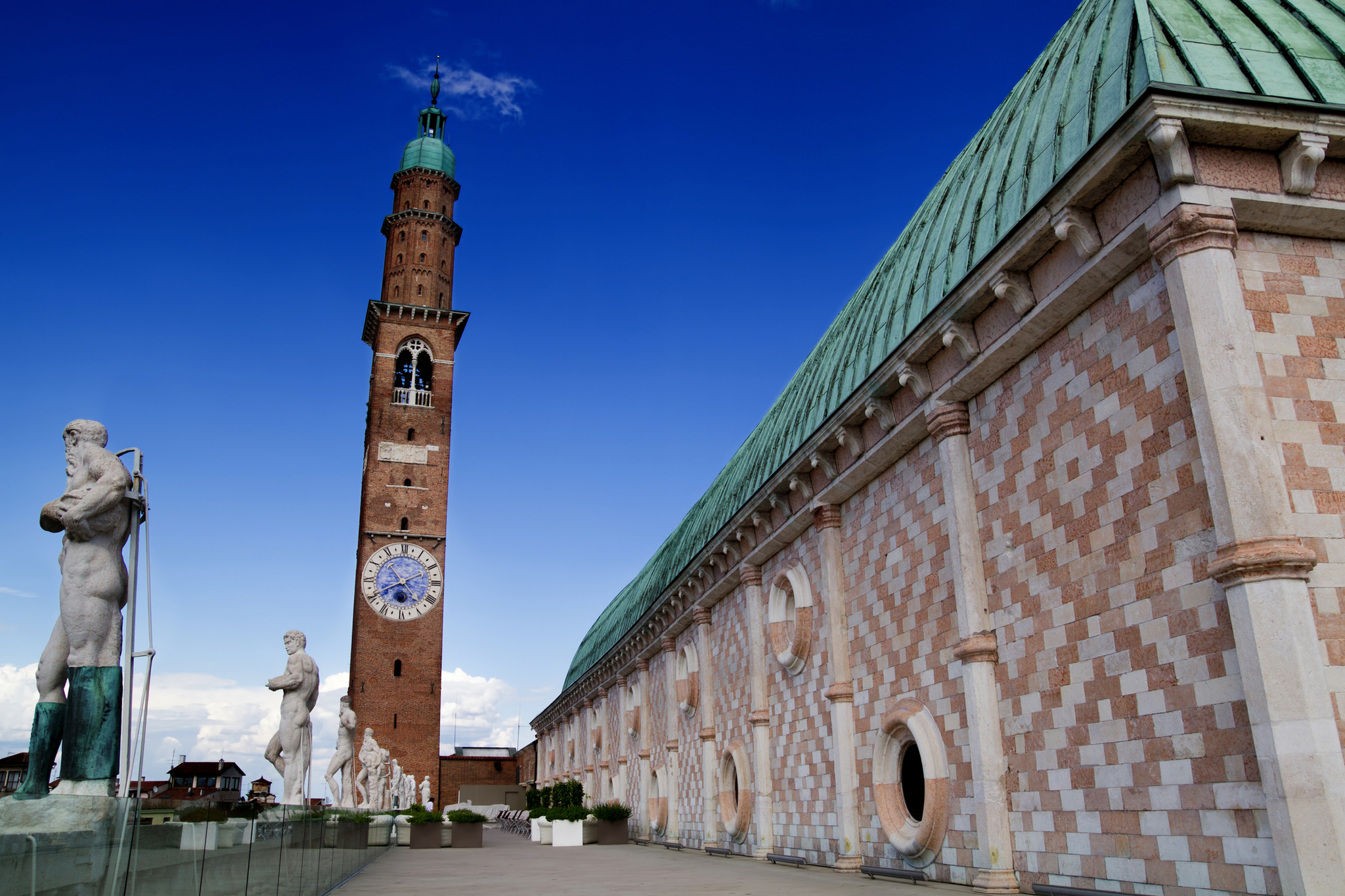 Historisches Gebäude mit Uhrturm und Statuen, blauer Himmel.