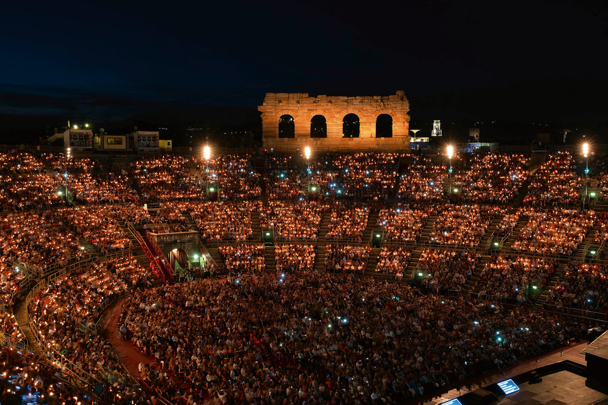 Beleuchtete Arena in Verona bei Nacht mit großem Publikum.