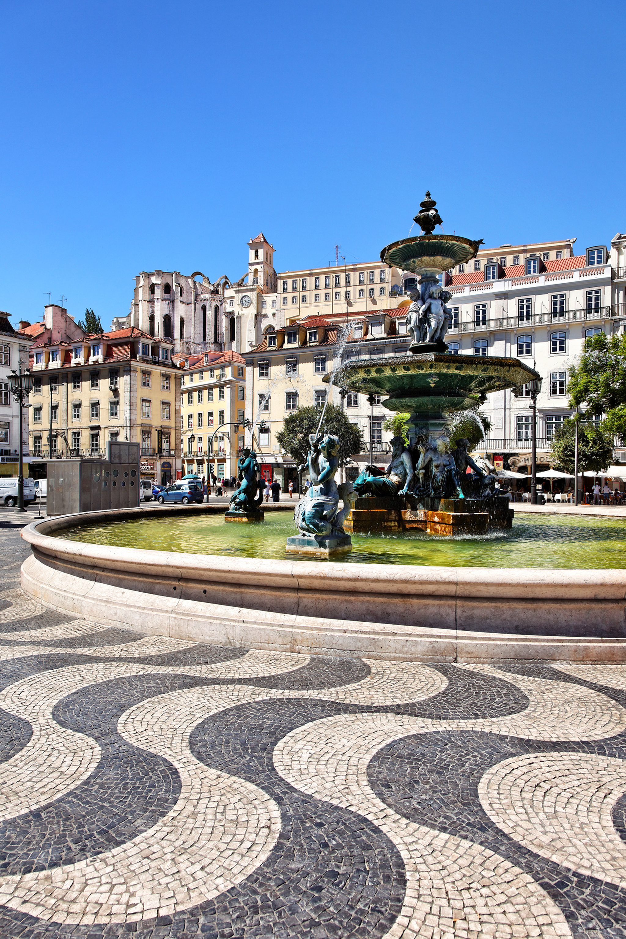 Platz mit historischer Architektur und großer Brunnenanlage im Vordergrund.