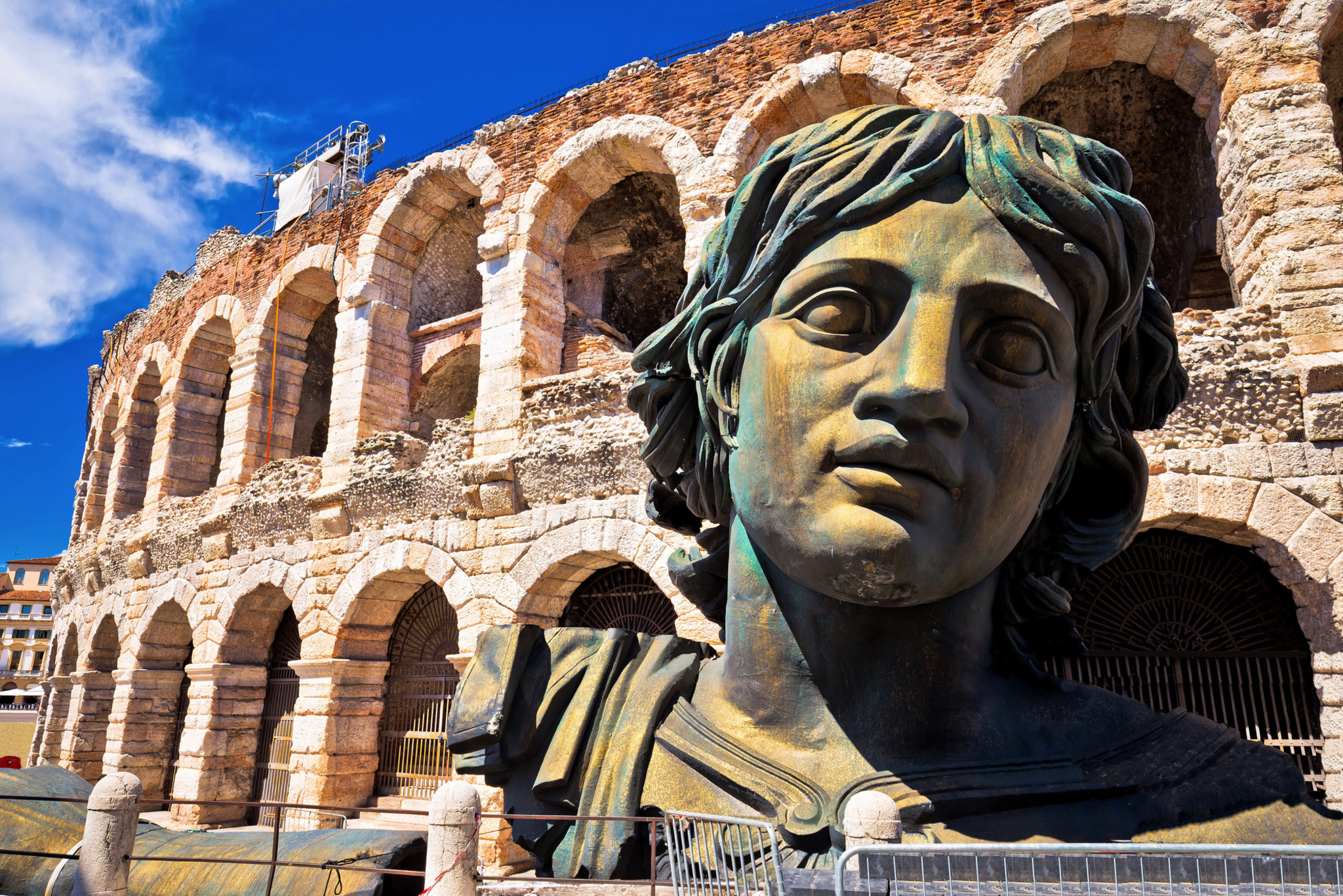 Büste vor einem antiken Amphitheater aus Stein mit Bögen.