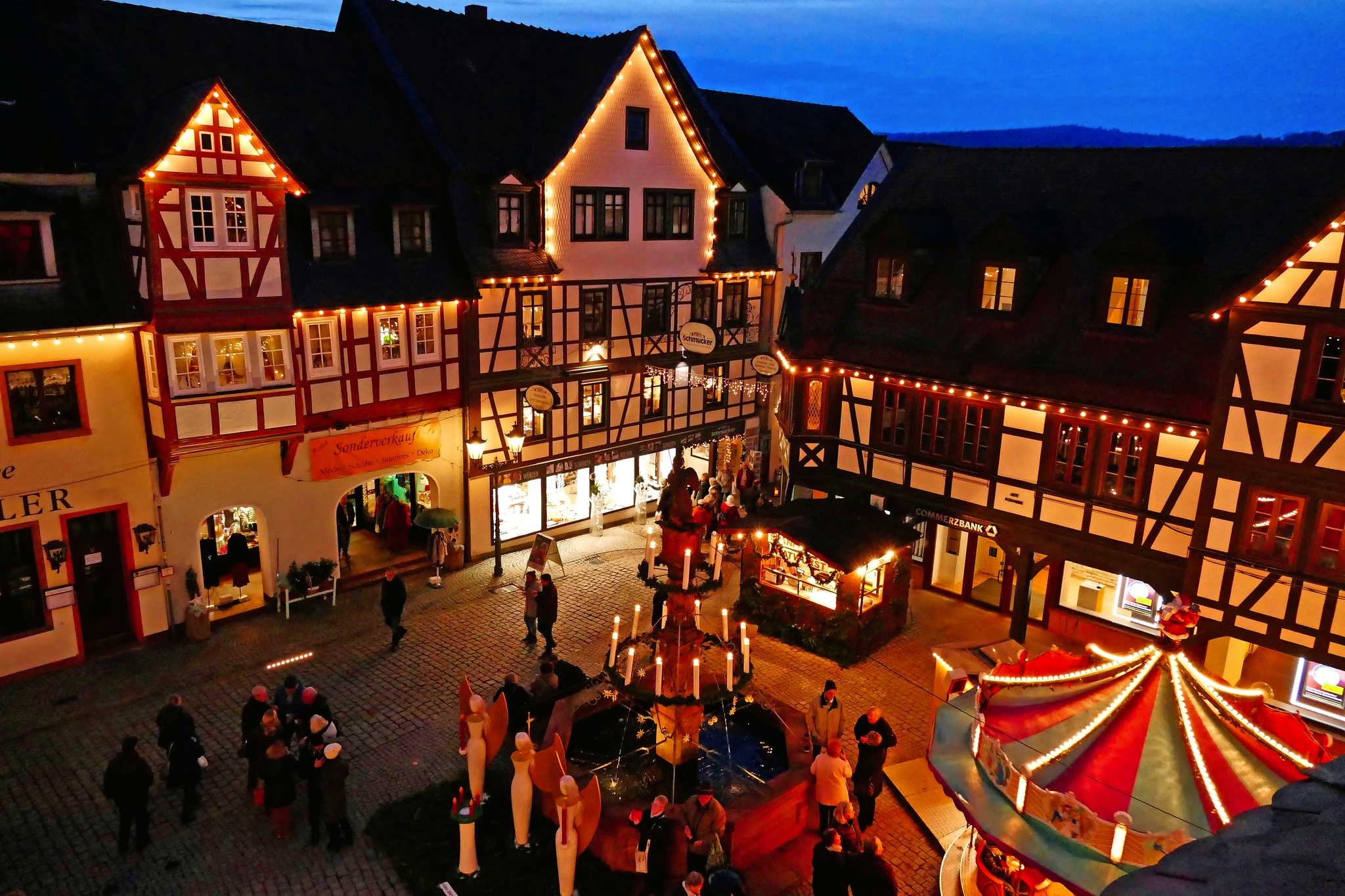 Historischer Weihnachtsmarkt mit Fachwerkhäusern bei Nacht, beleuchtet.