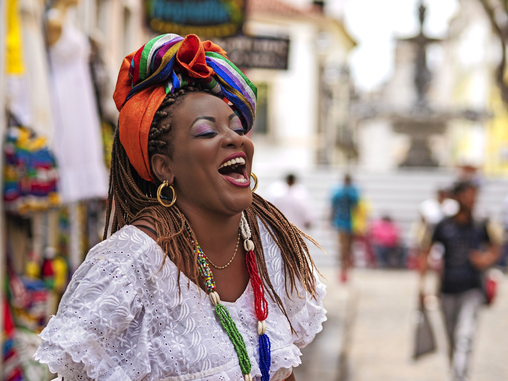 Frau in traditioneller Kleidung lacht auf einer belebten Straße.
