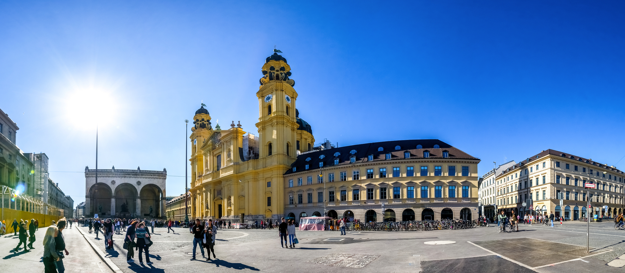 Menschen auf einem sonnigen Platz mit historischer Architektur.