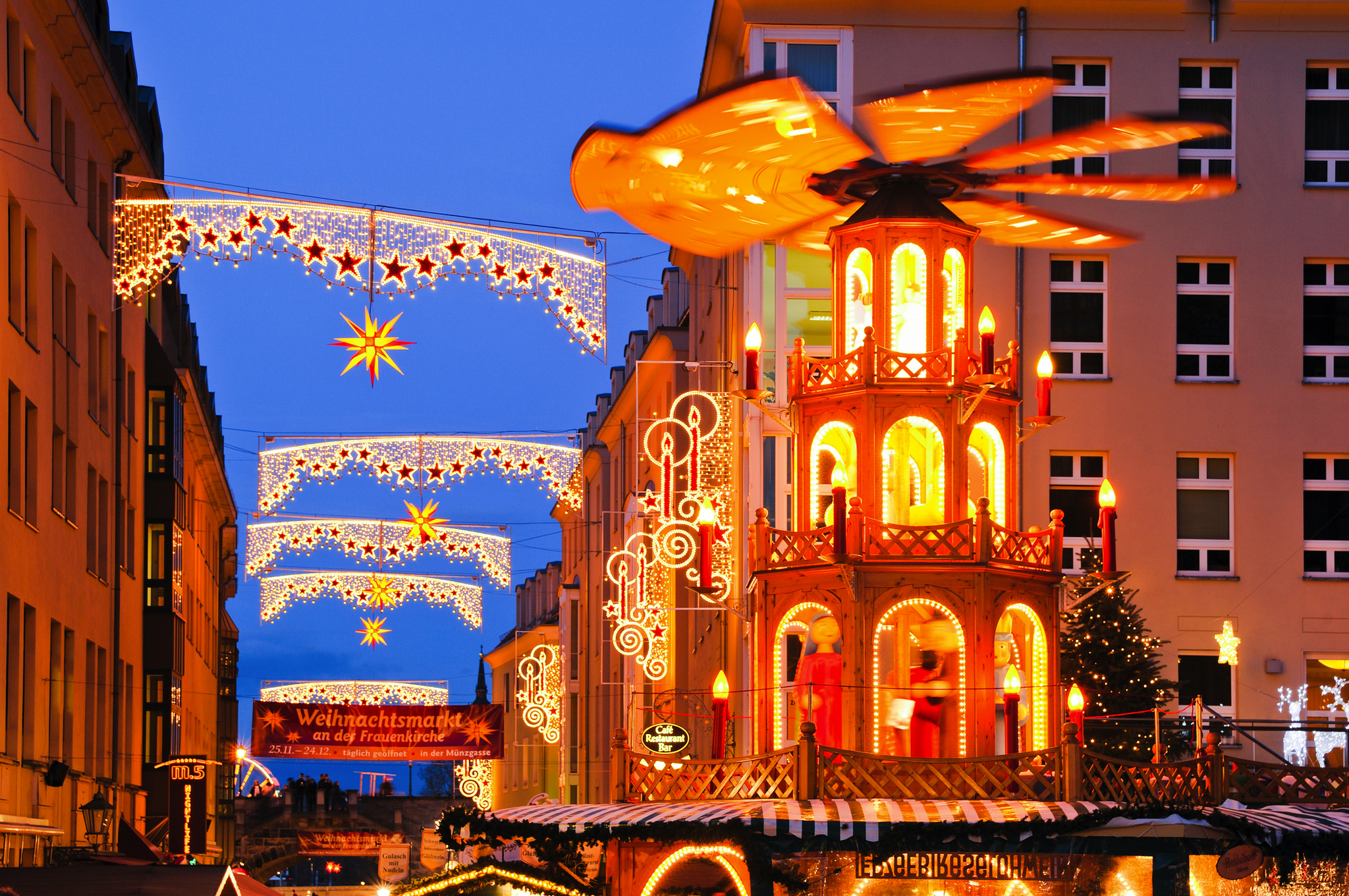 Weihnachtsmarkt mit beleuchteter Pyramide und Sternendekorationen bei Nacht.