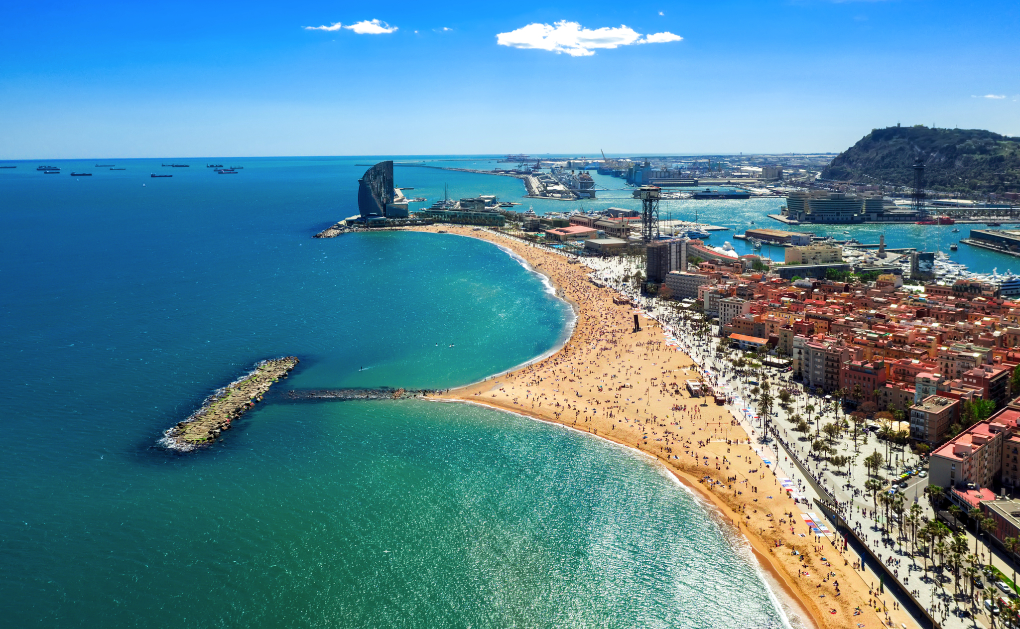 Strand von Barcelona mit Blick auf das Meer und Stadtgebäude im Hintergrund.