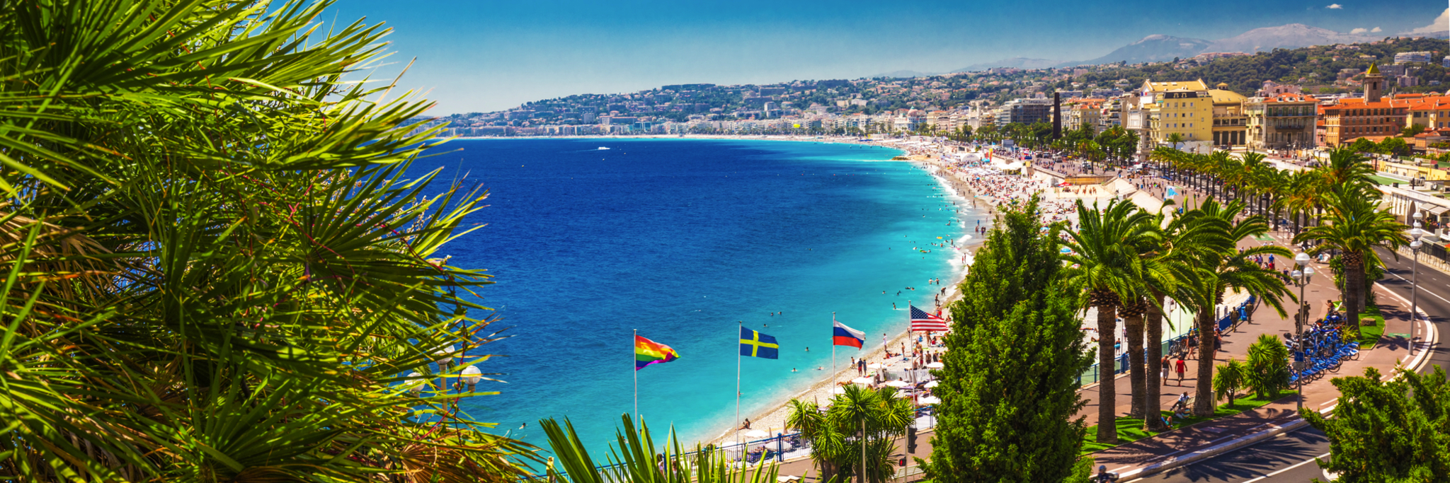 Blick auf eine Küstenstadt mit Strand, Palmen und blauem Meer.