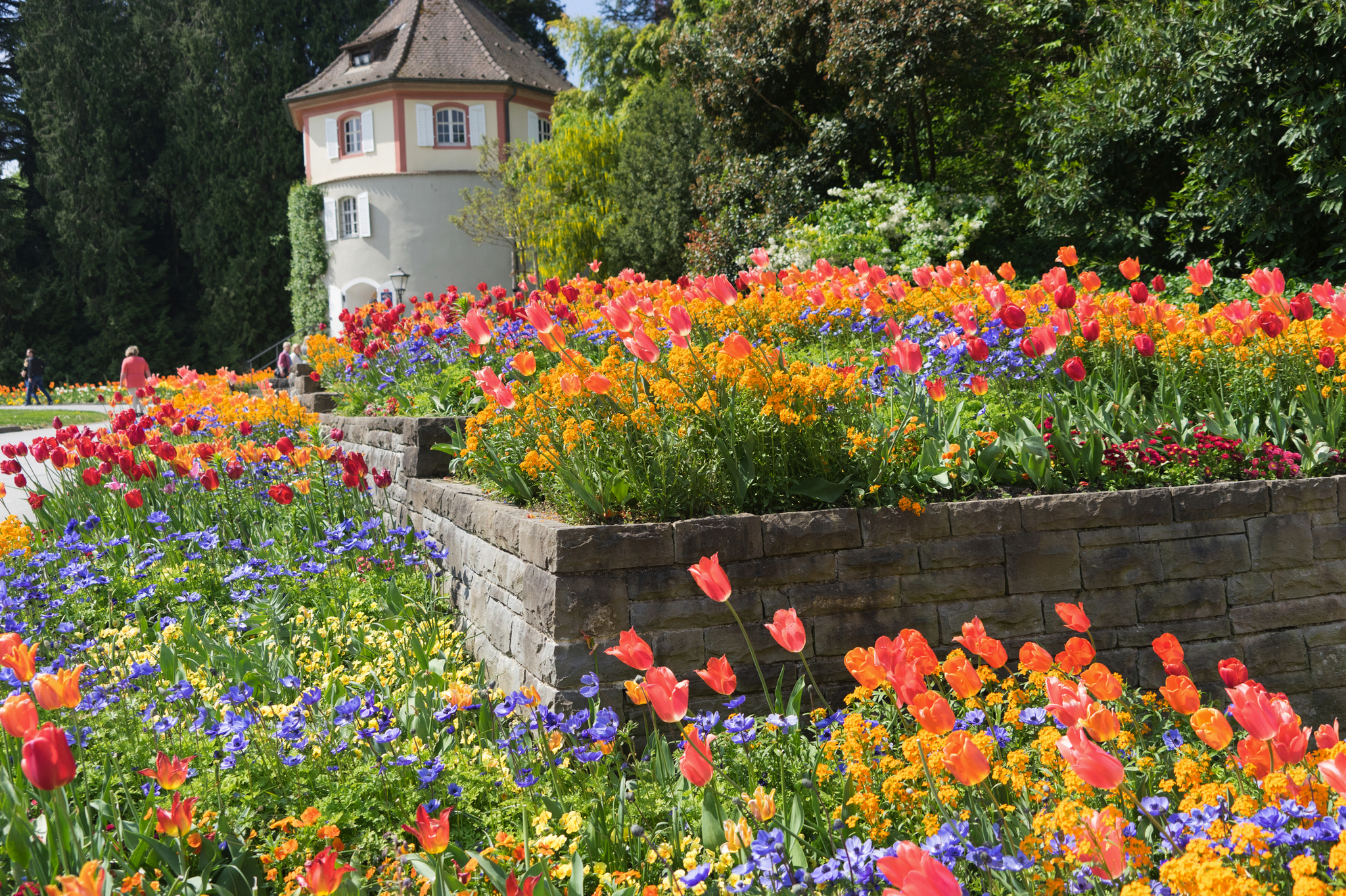 Bunter Blumengarten vor einem runden Gebäude im Frühling.