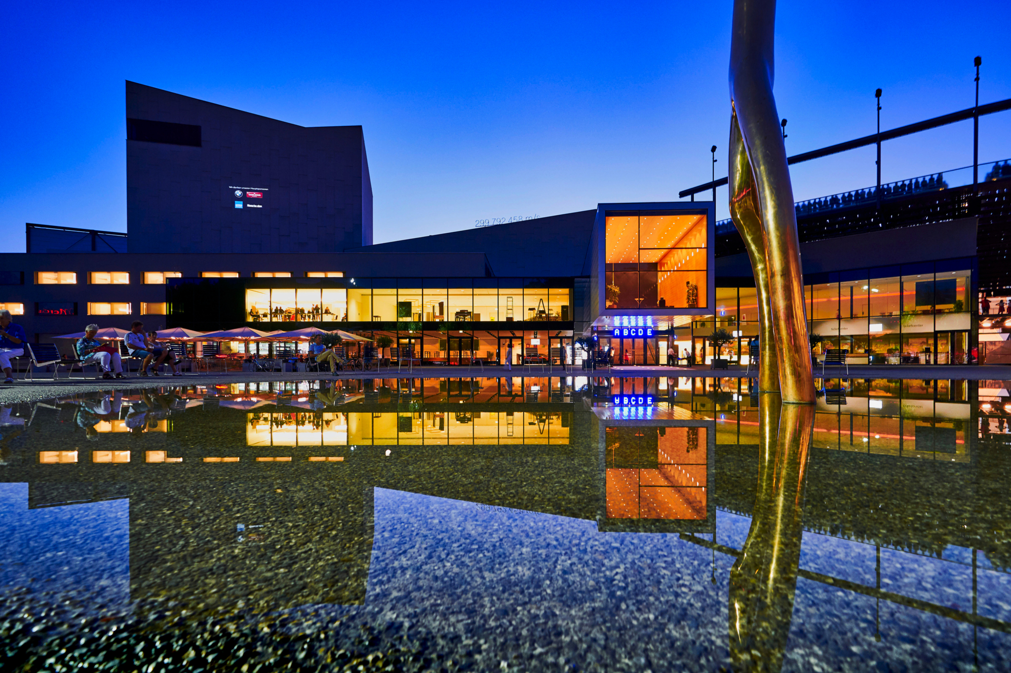 Beleuchtetes Gebäude am Wasser bei Dämmerung mit Spiegelung.