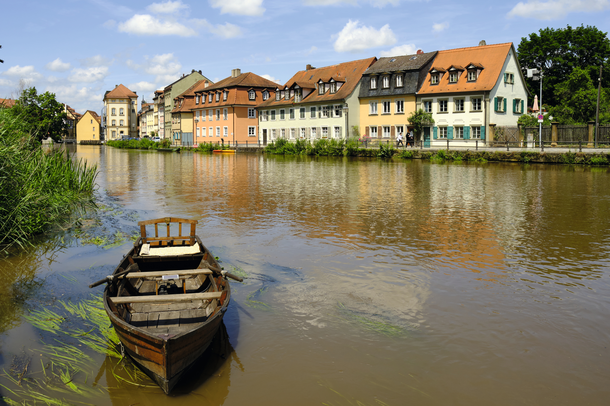 Holzboot auf einem Fluss vor bunten alten Häusern.