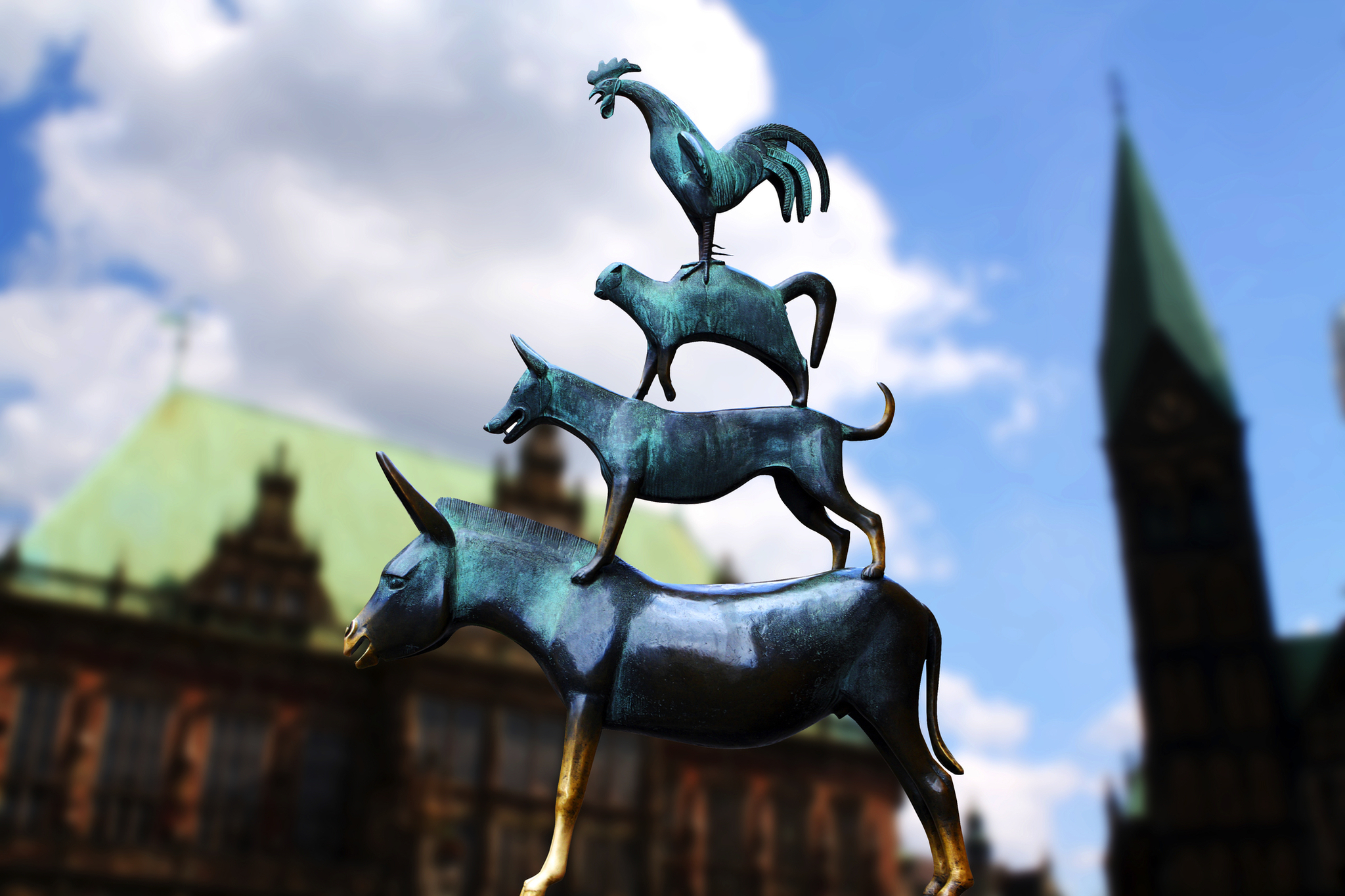 Skulptur der Bremer Stadtmusikanten vor unscharfem Gebäude im Hintergrund.