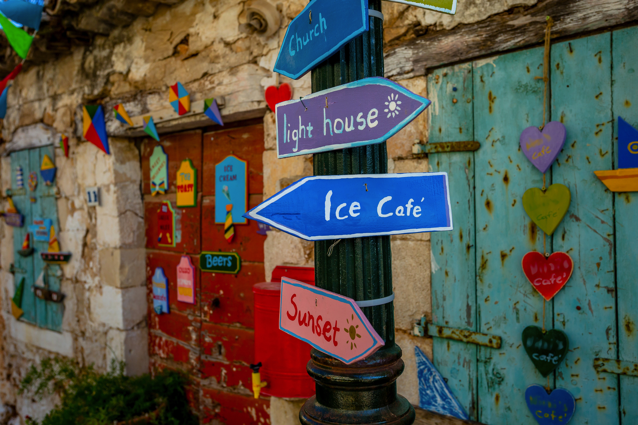 Bunte Schilder an einer Steinwand zeigen in verschiedene Richtungen.