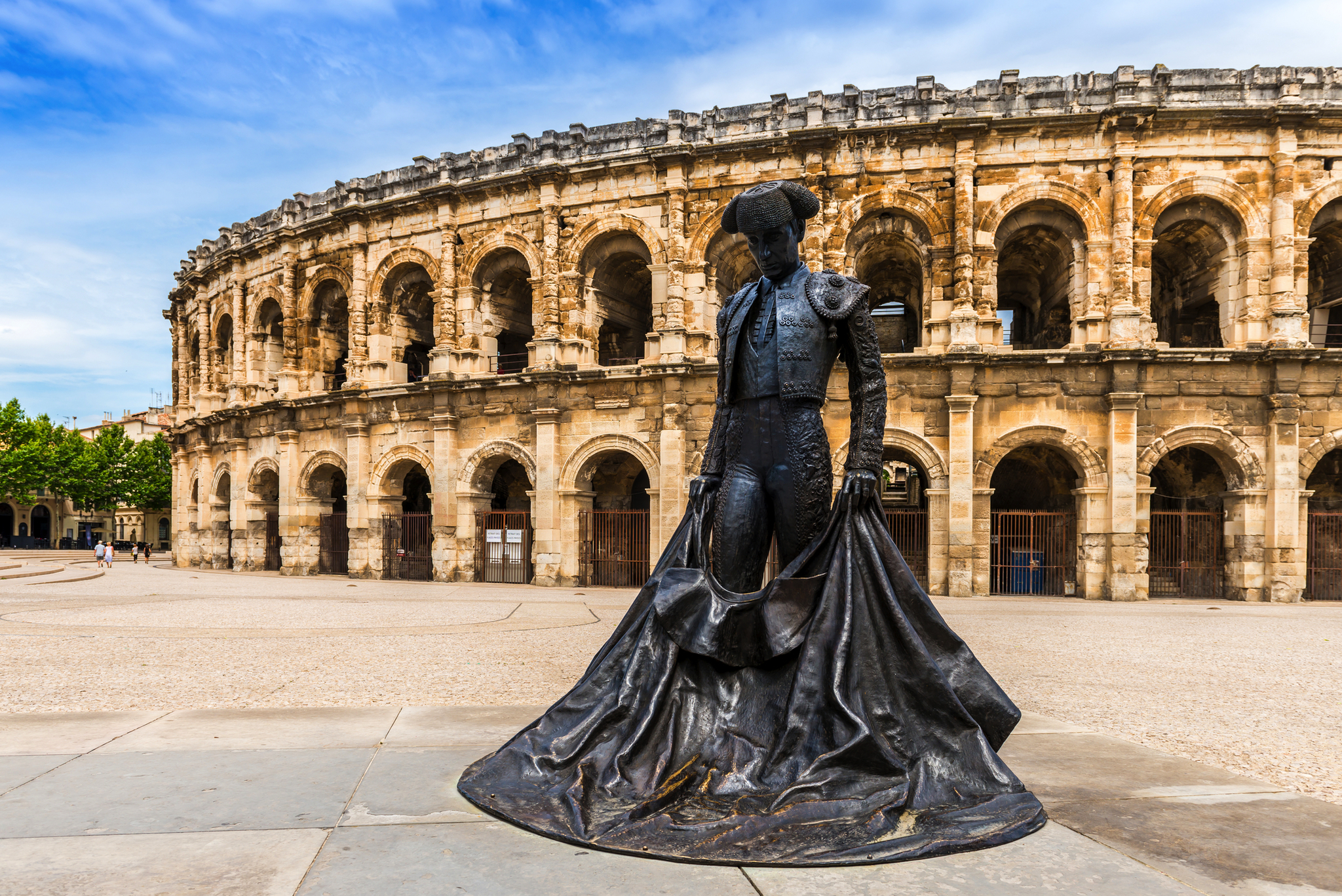 Stierkämpferstatue vor antikem römischen Amphitheater.