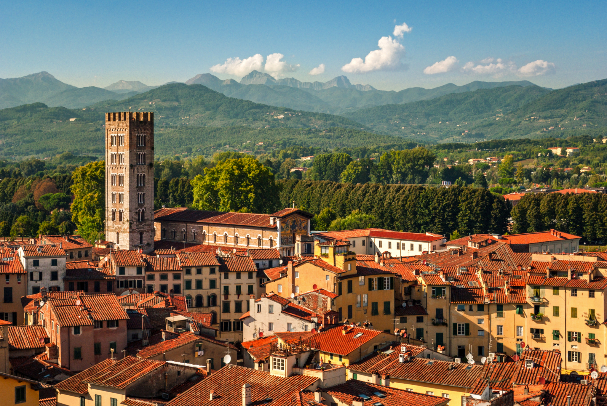 Lucca in der Toskana Blick auf historische Stadt mit Kirchturm und Bergen im Hintergrund.