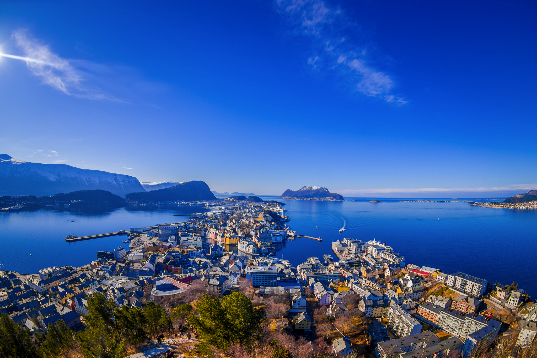 Luftaufnahme einer Küstenstadt mit Bergen und blauem Himmel.