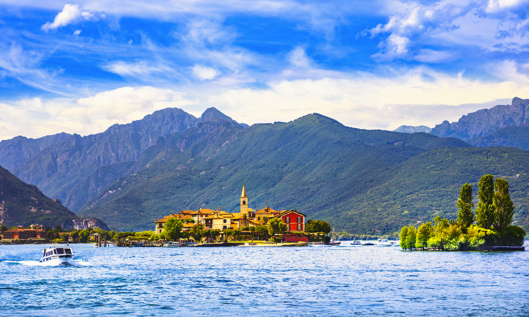 Insel mit Gebäuden auf einem See, Berge im Hintergrund.