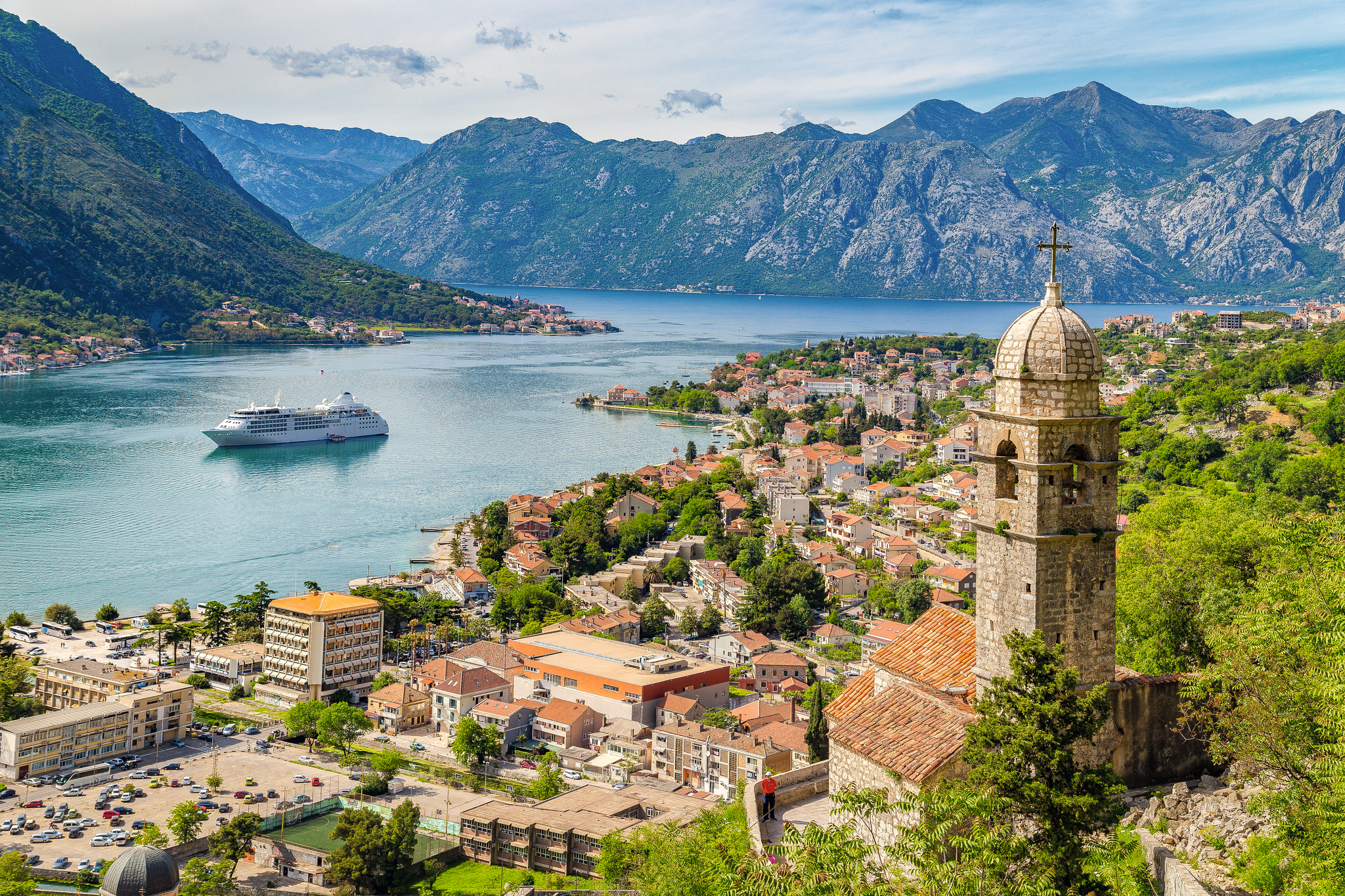 Küstenstadt Kotor mit Kreuzfahrtschiff und Bergen im Hintergrund.