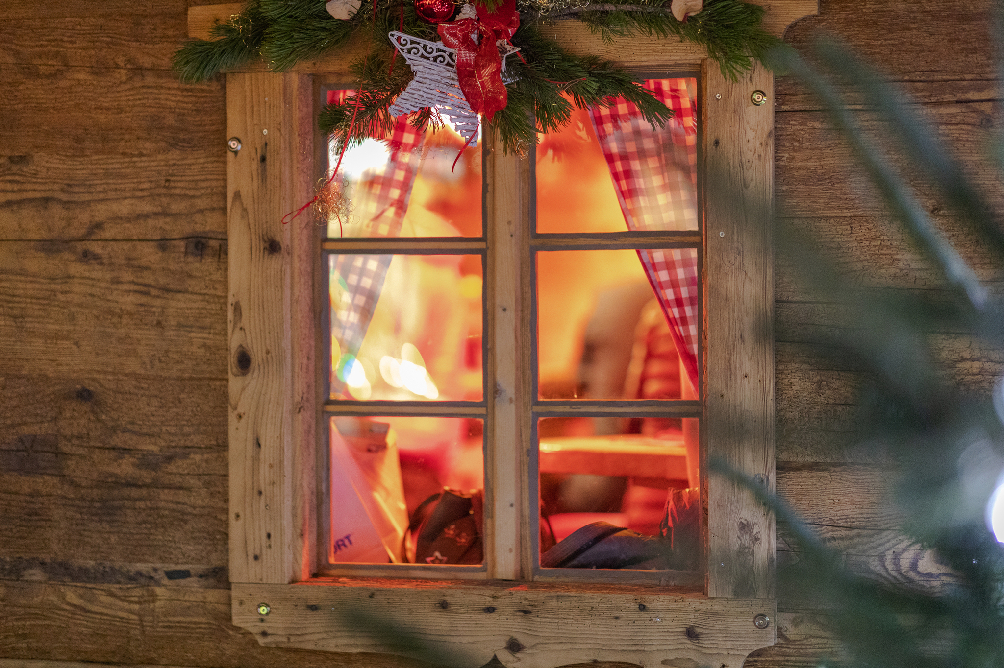 Beleuchtetes Fenster mit Holzrahmen und Weihnachtsdekoration.