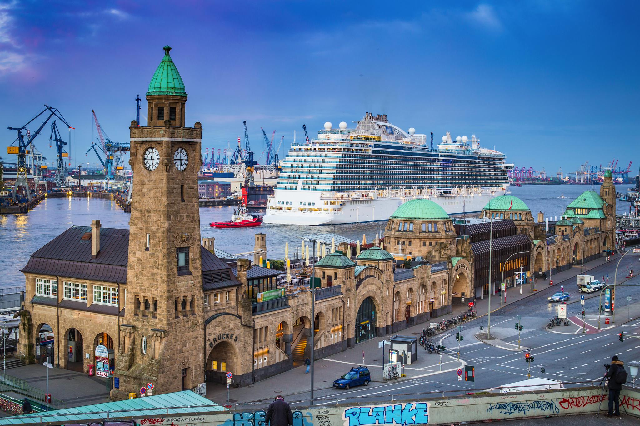 Kreuzfahrtschiff an den Landungsbrücken in Hamburg mit Blick auf historische Gebäude und Hafen.