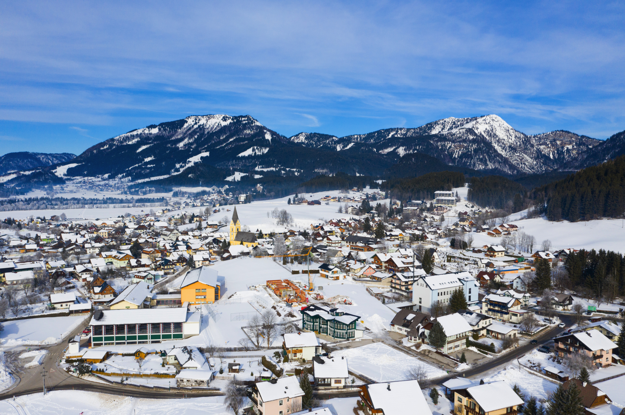 Verschneite Stadt in Alpenlandschaft mit Bergen im Hintergrund.