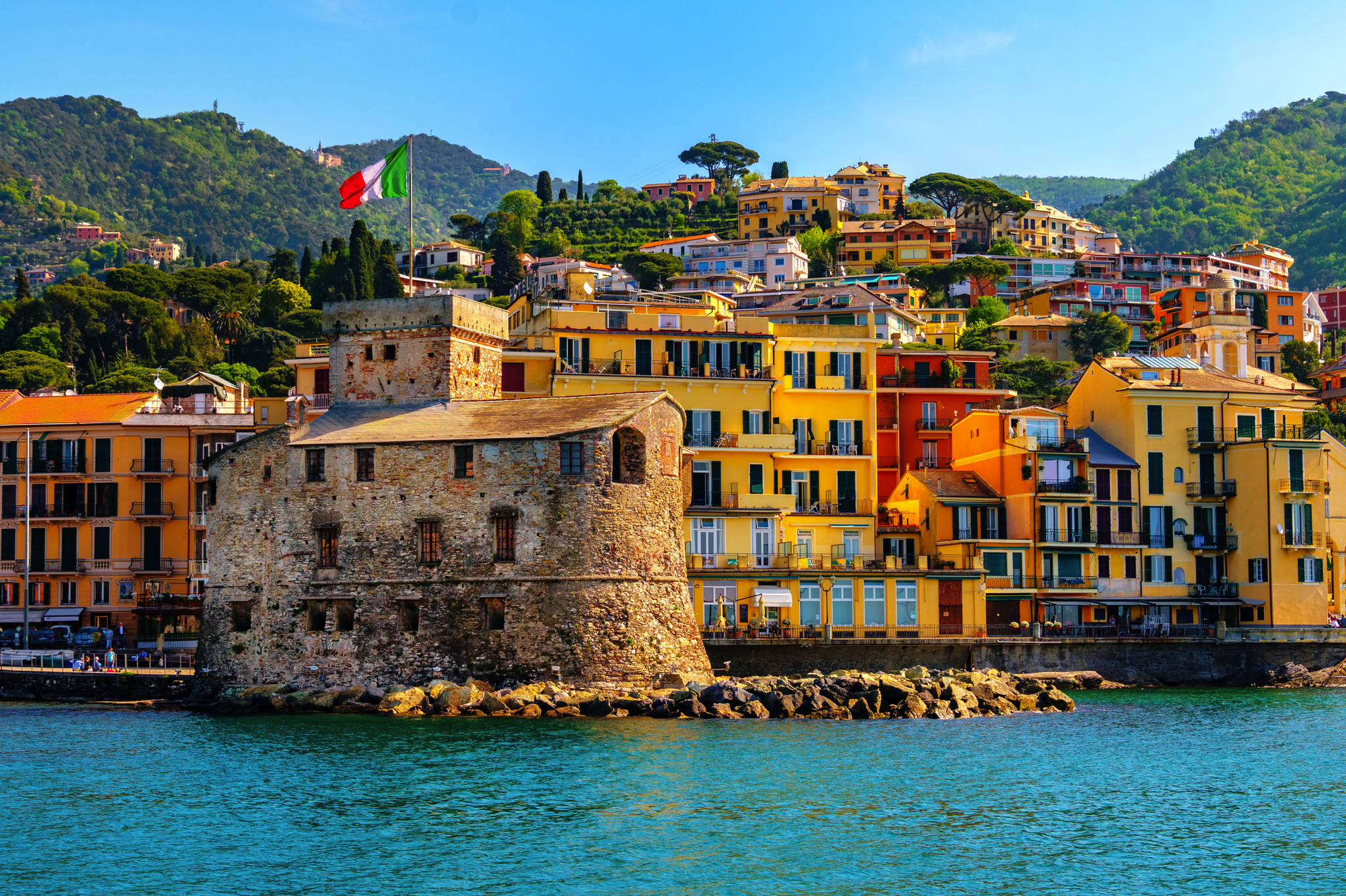 Festung und bunte Häuser am Meer mit Bergen im Hintergrund