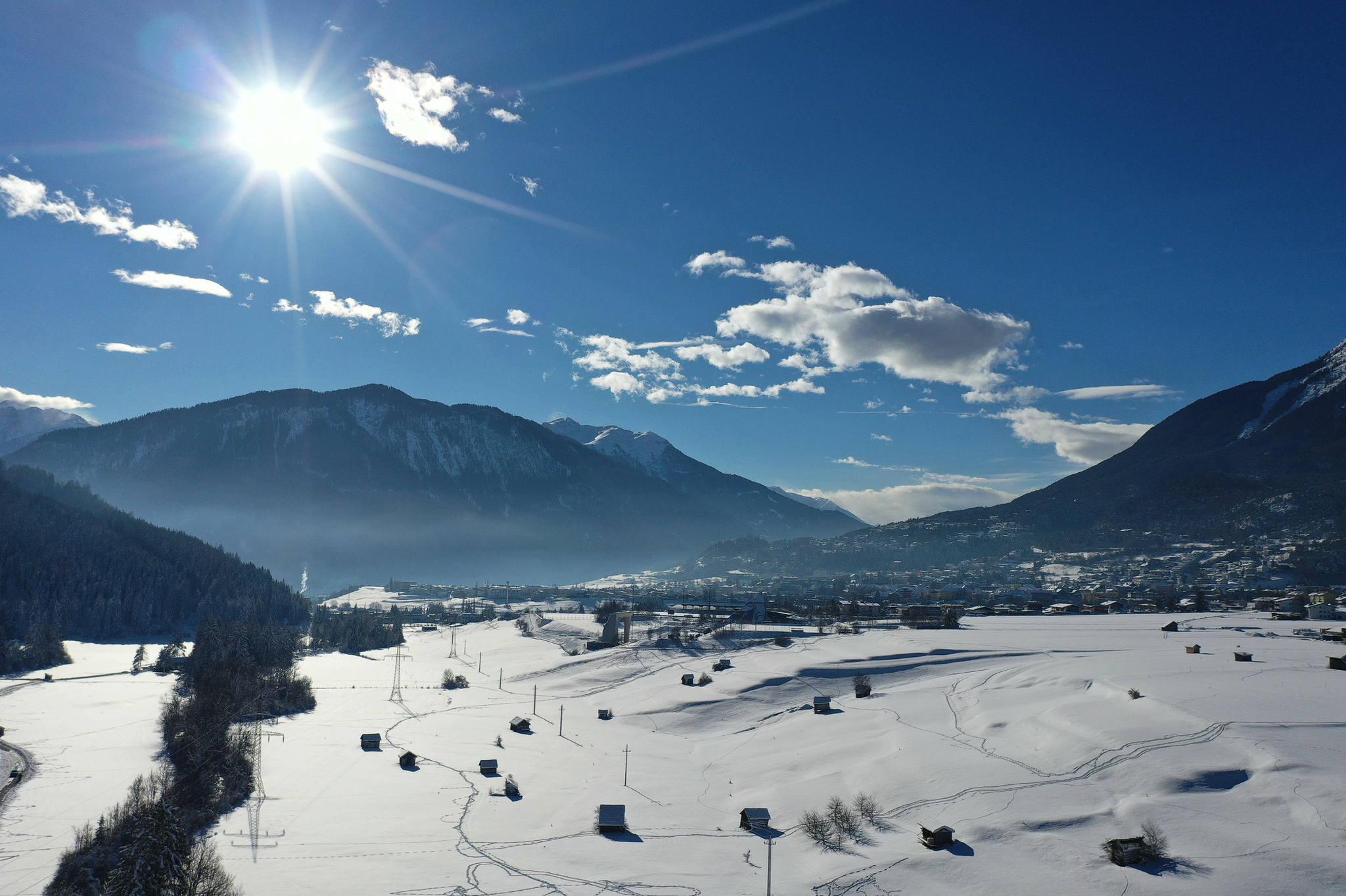 Verschneite Landschaft mit Bergen und strahlendem Sonnenschein.
