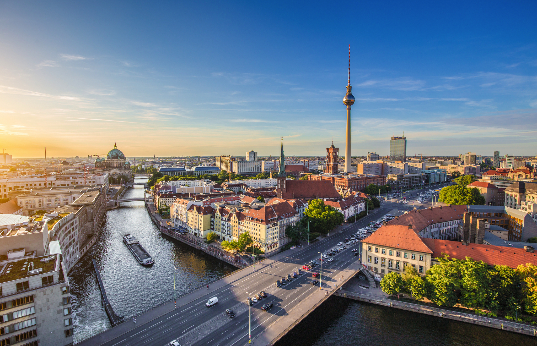 Stadtbild von Berlin mit Fernsehturm und Fluss bei Sonnenuntergang.