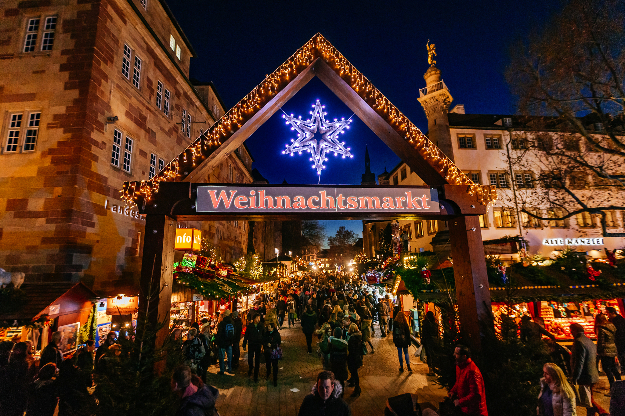 Eingangstor zum Stuttgarter Weihnachtsmarkt bei Nacht vor historischen Gebäuden.