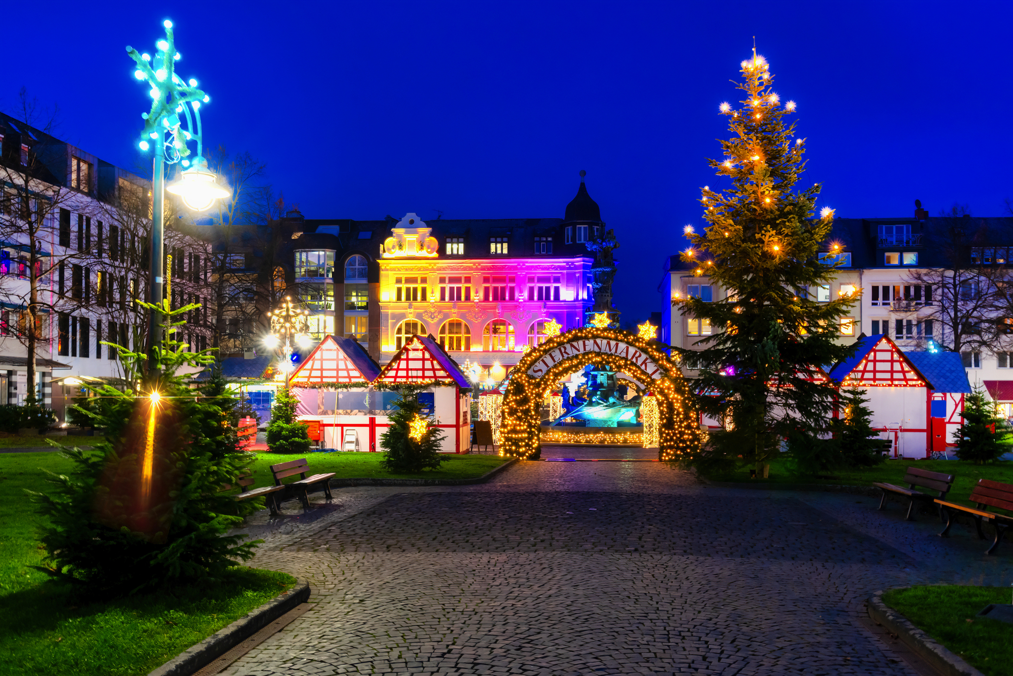 Weihnachtsmarkt am Abend mit bunten Lichtern und geschmücktem Weihnachtsbaum