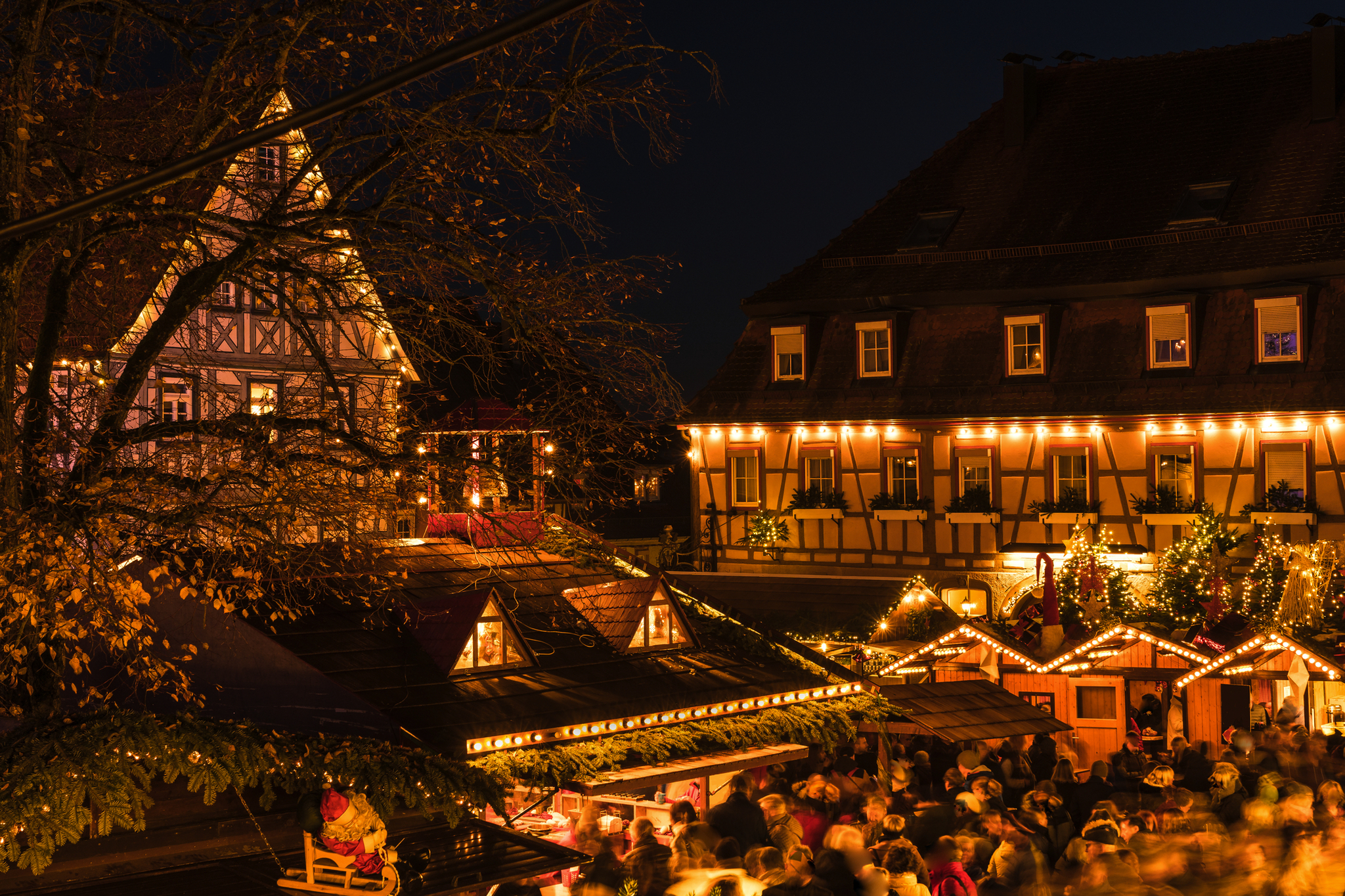 Abendlicher Weihnachtsmarkt mit Fachwerkhäusern und Lichterdekoration.
