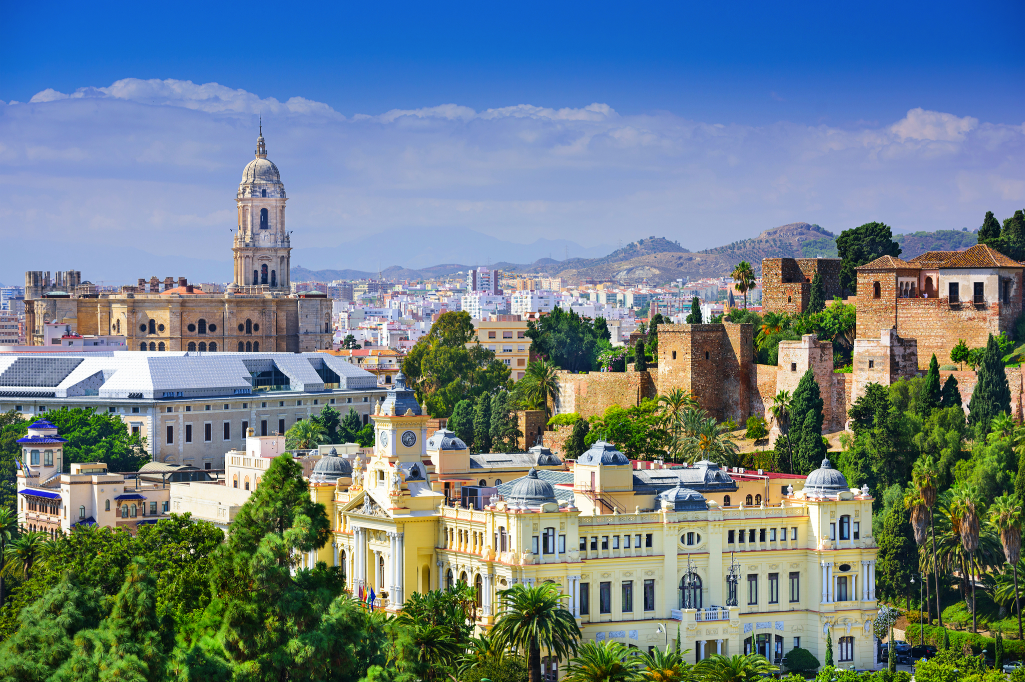 Blick auf historische Gebäude in Málaga, Spanien, umgeben von Hügeln und Vegetation.