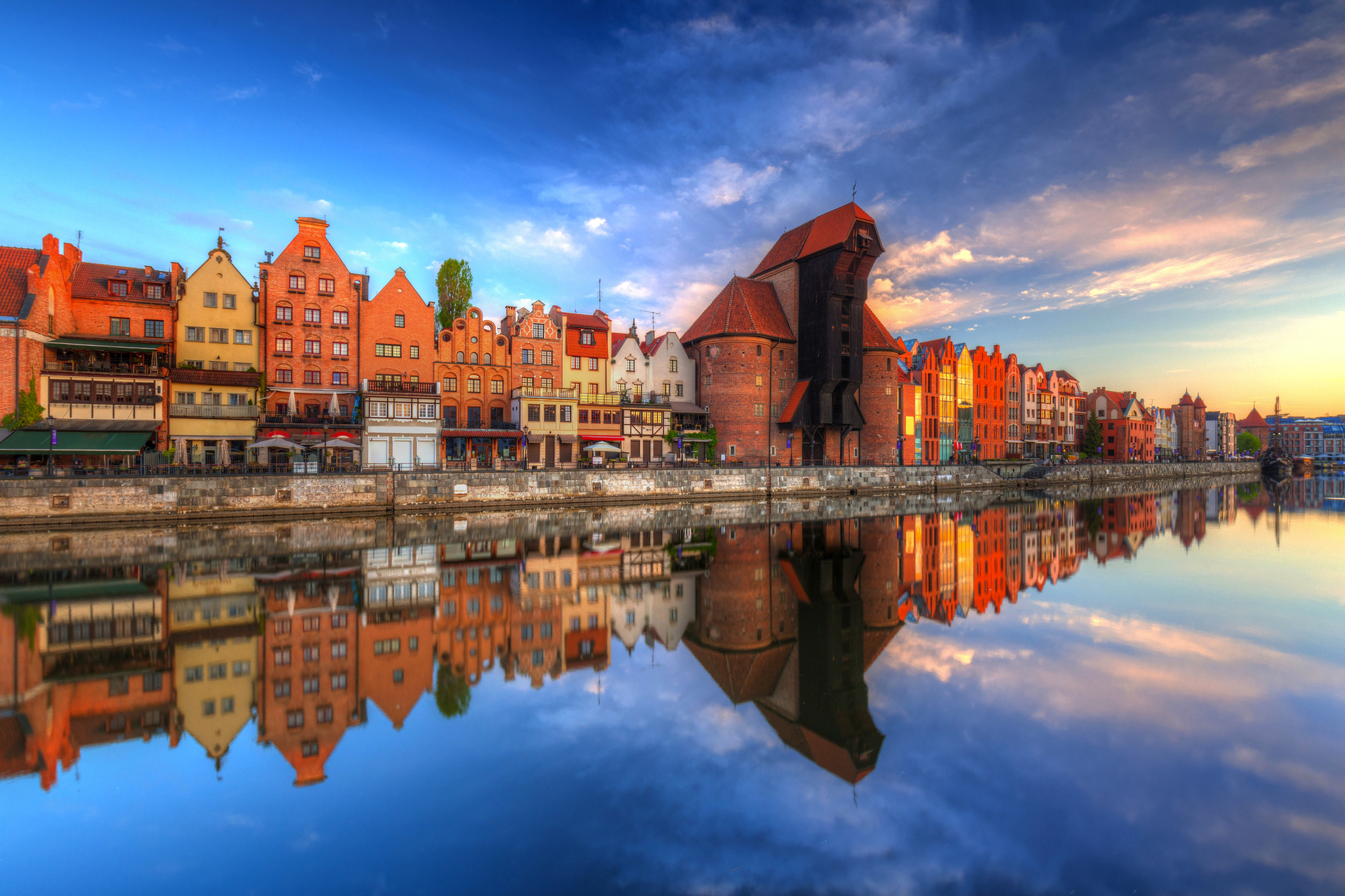 Bunte Gebäude spiegeln sich im Wasser eines Flusses bei Sonnenuntergang.
