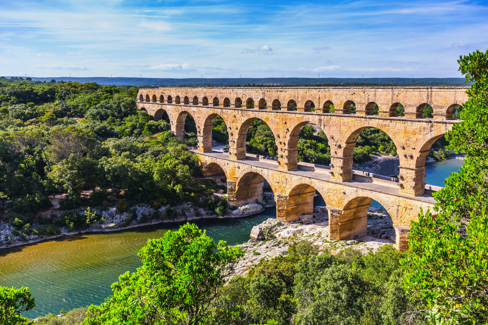 Pont du Gard, römischer Aquädukt über einen Fluss in bewaldeter Landschaft.