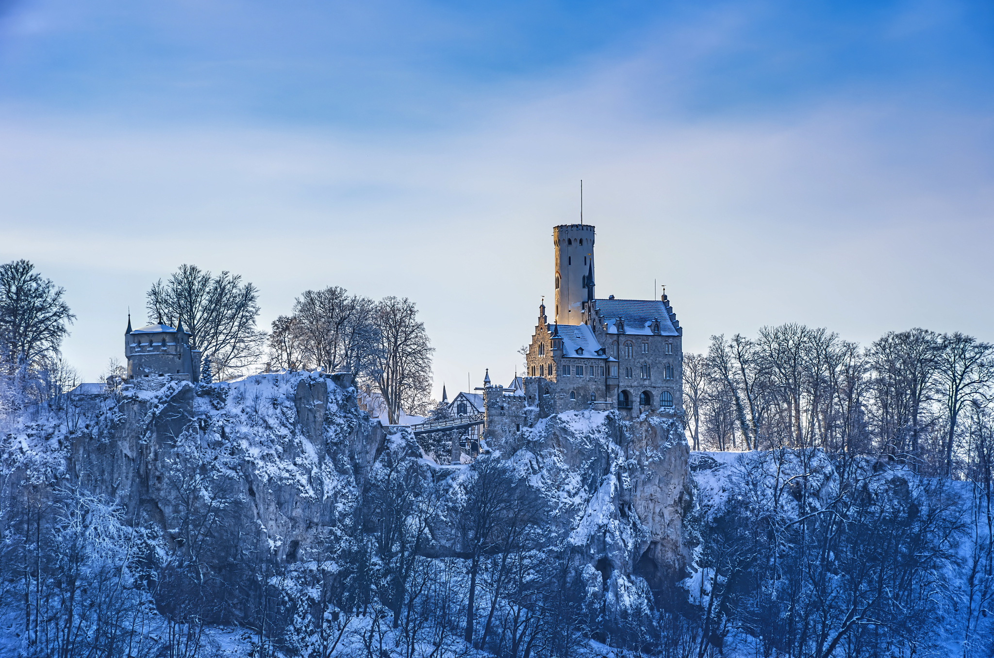 Schloss auf schneebedecktem Hügel im Winter bei blauem Himmel.
