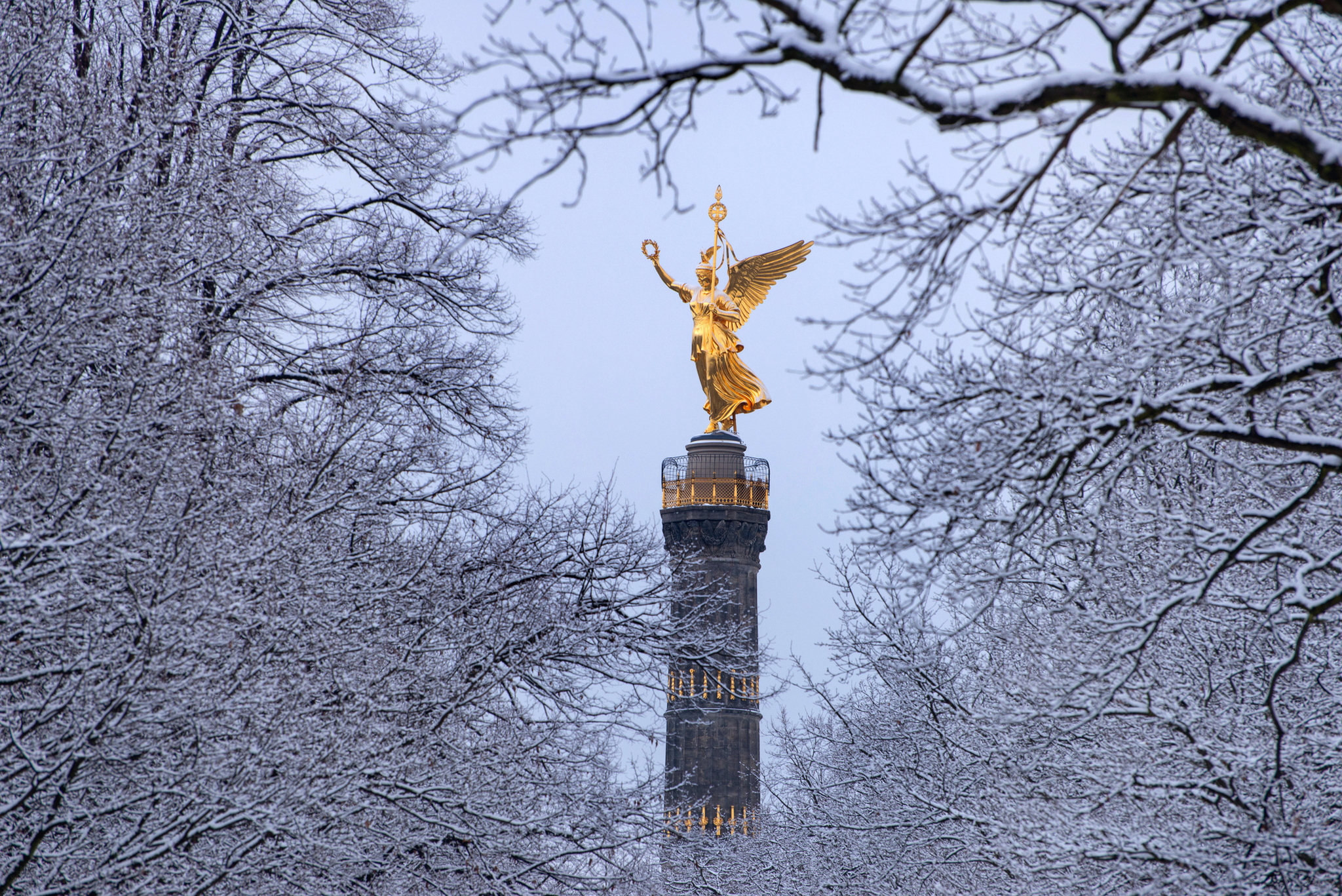 Siegessäule in Berlin, umgeben von schneebedeckten Bäumen im Winter.
